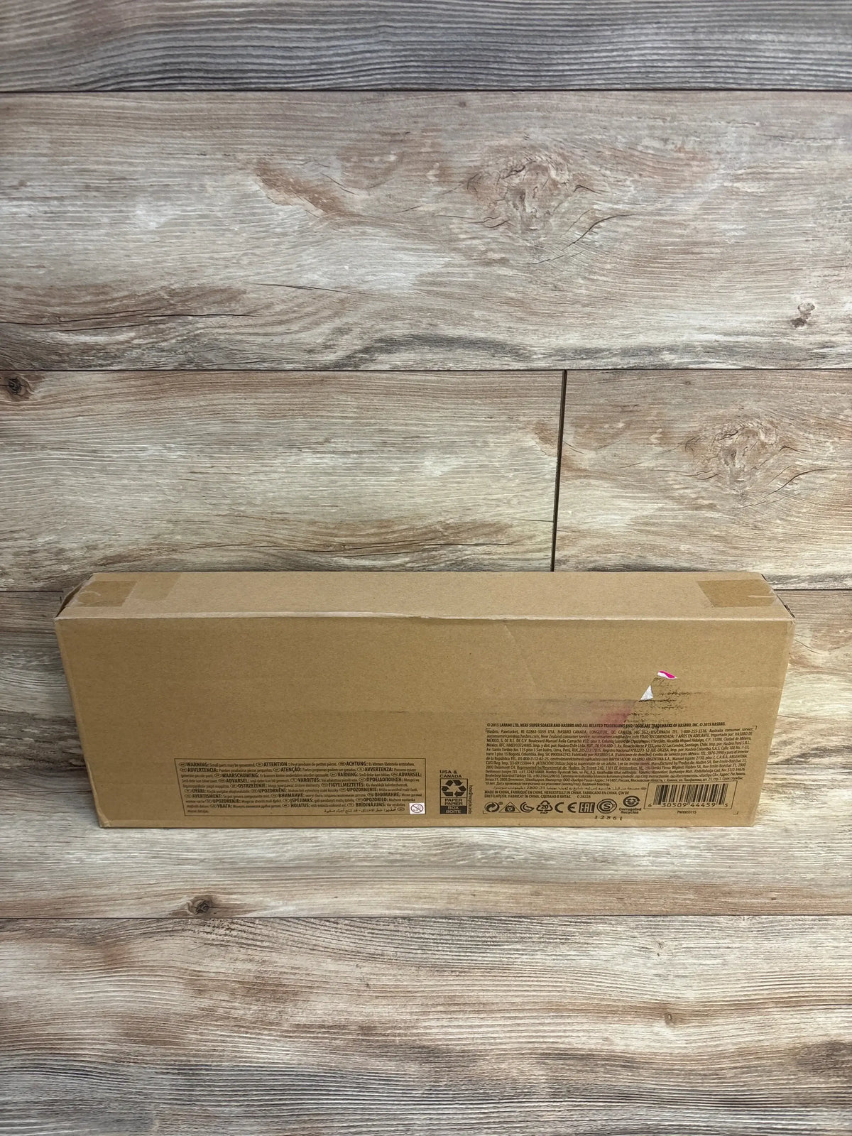 Back of Nerf Super Soaker Barrage box, sealed brown cardboard with manufacturer labels on wood background