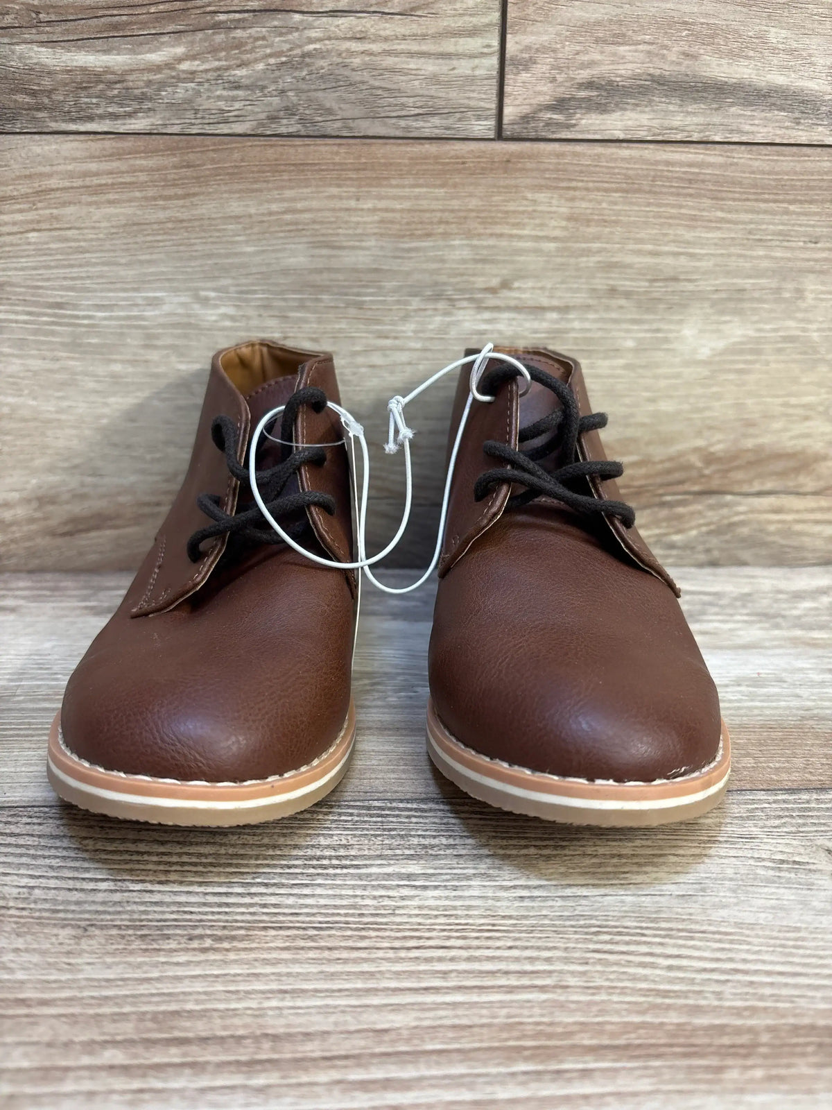Pair of brown toddler lace-up boots with rubber soles on wood background