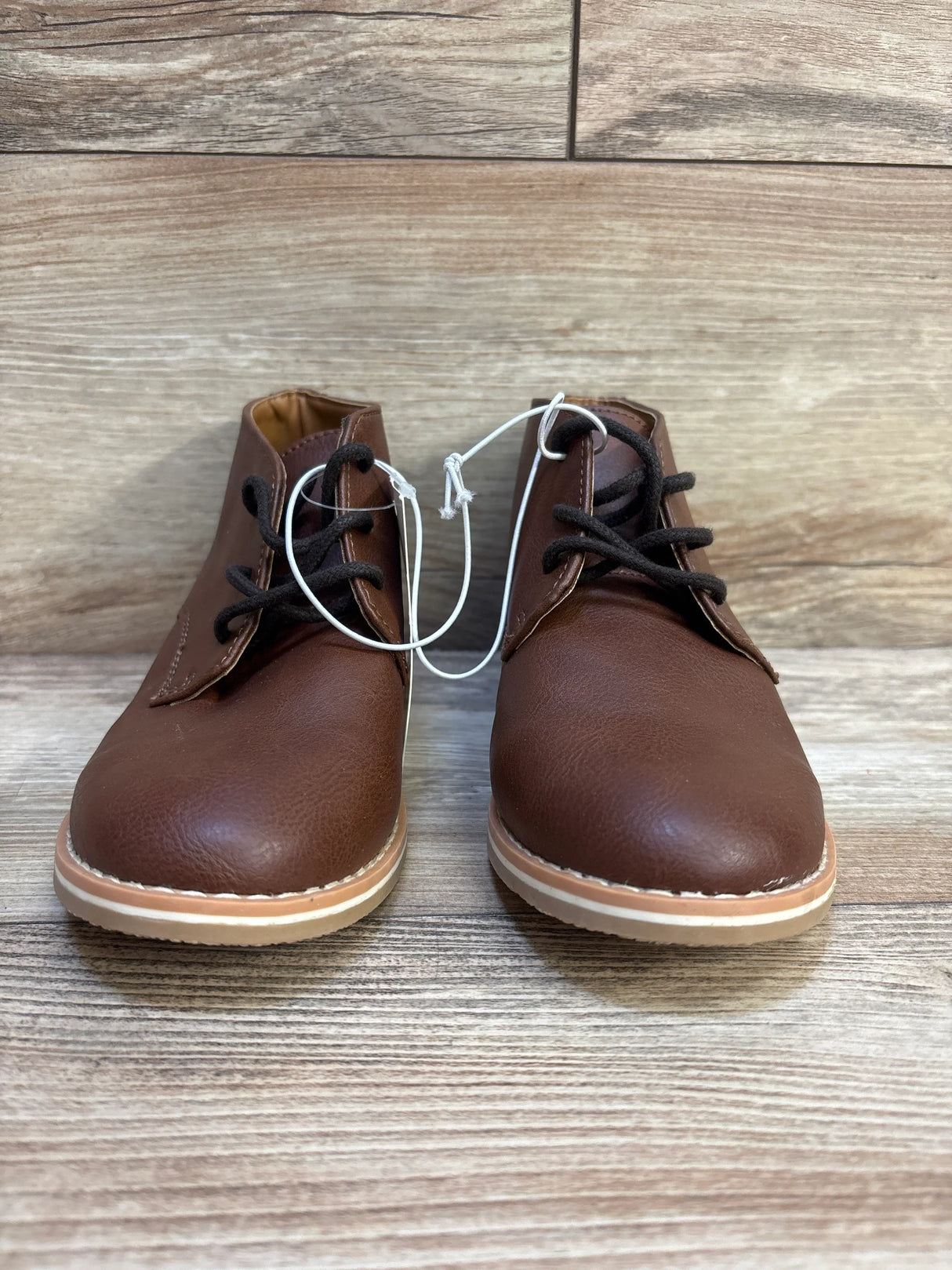 Pair of brown toddler lace-up boots with rubber soles on wood background
