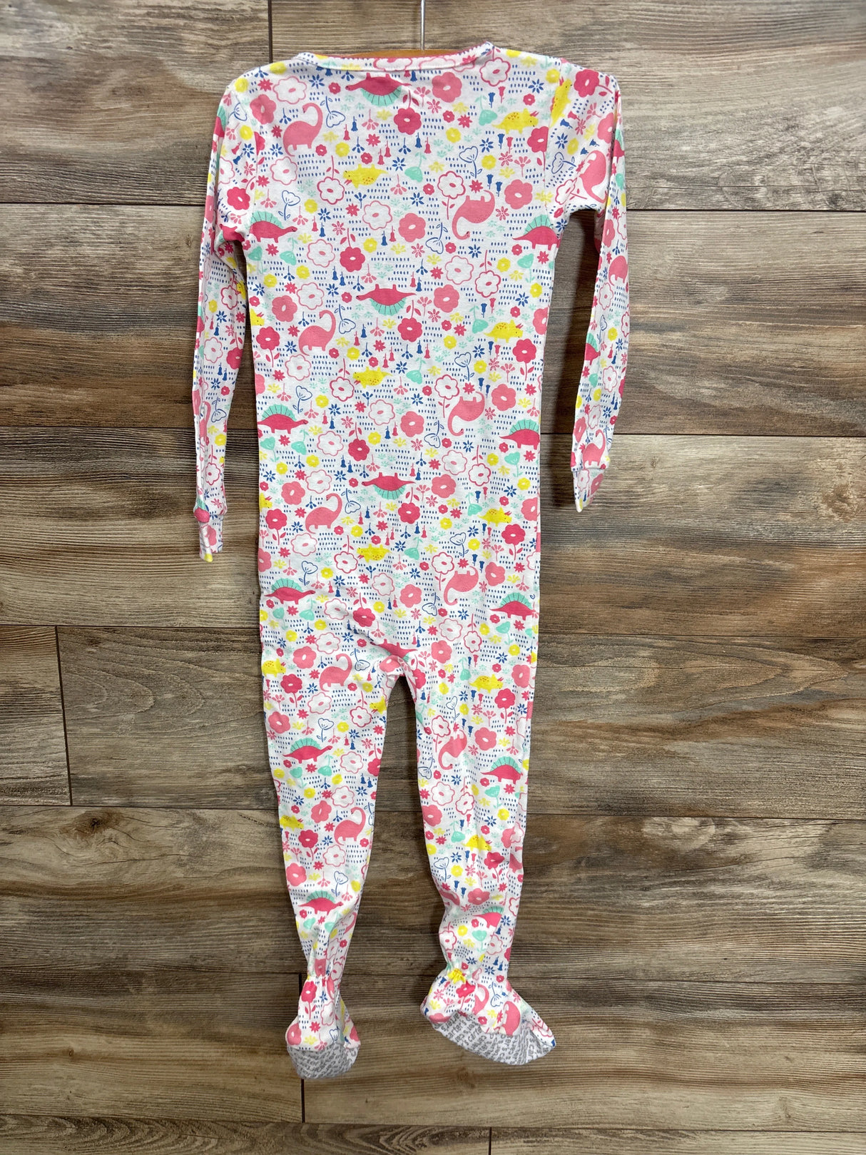 Colorful baby footed pajamas with pink dinosaurs, flowers, and blue dots on white, perfect for toddler sleepwear.