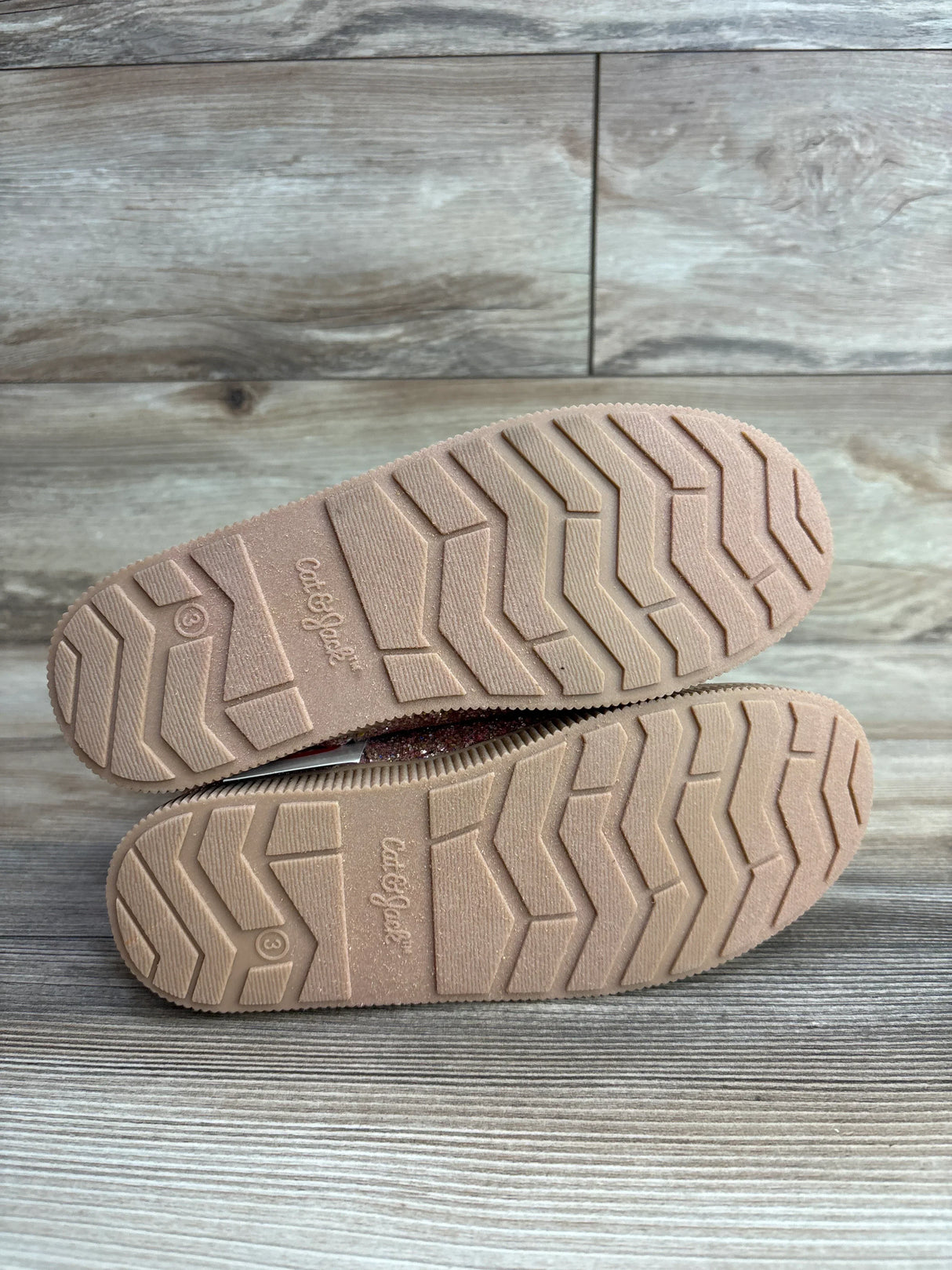 Bottom view of toddler shoes with non-slip rubber soles on wood floor