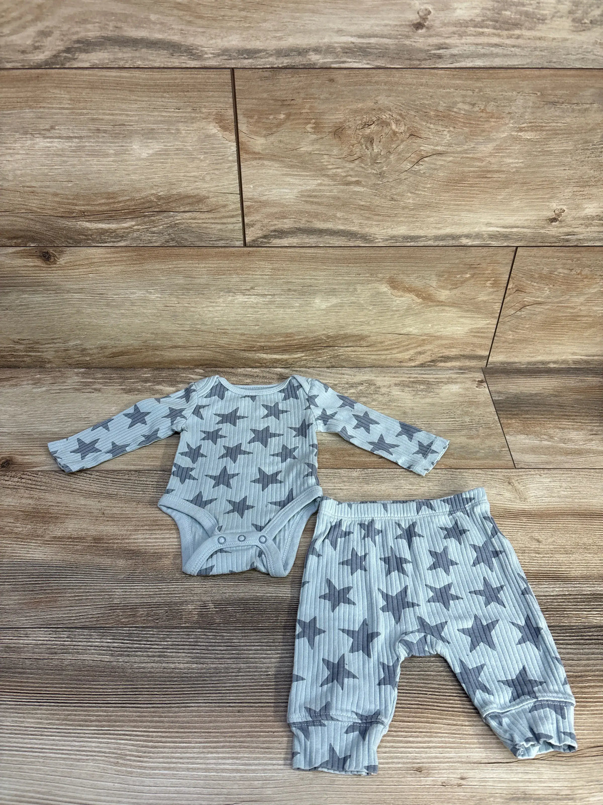 Top view of Cloud Island blue ribbed bodysuit and bottoms set showcasing star print on wood flooring