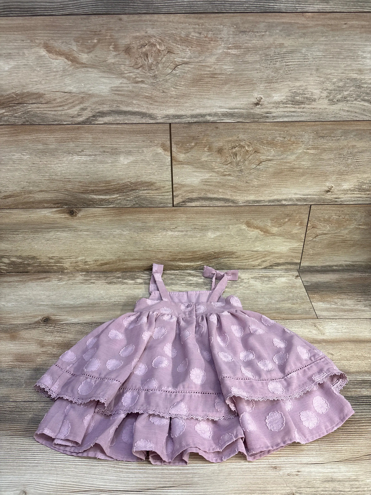 Front view of Sincerely Jules purple layered sleeveless dress in size 18 months showing tie straps and tiered skirt on a wood floor