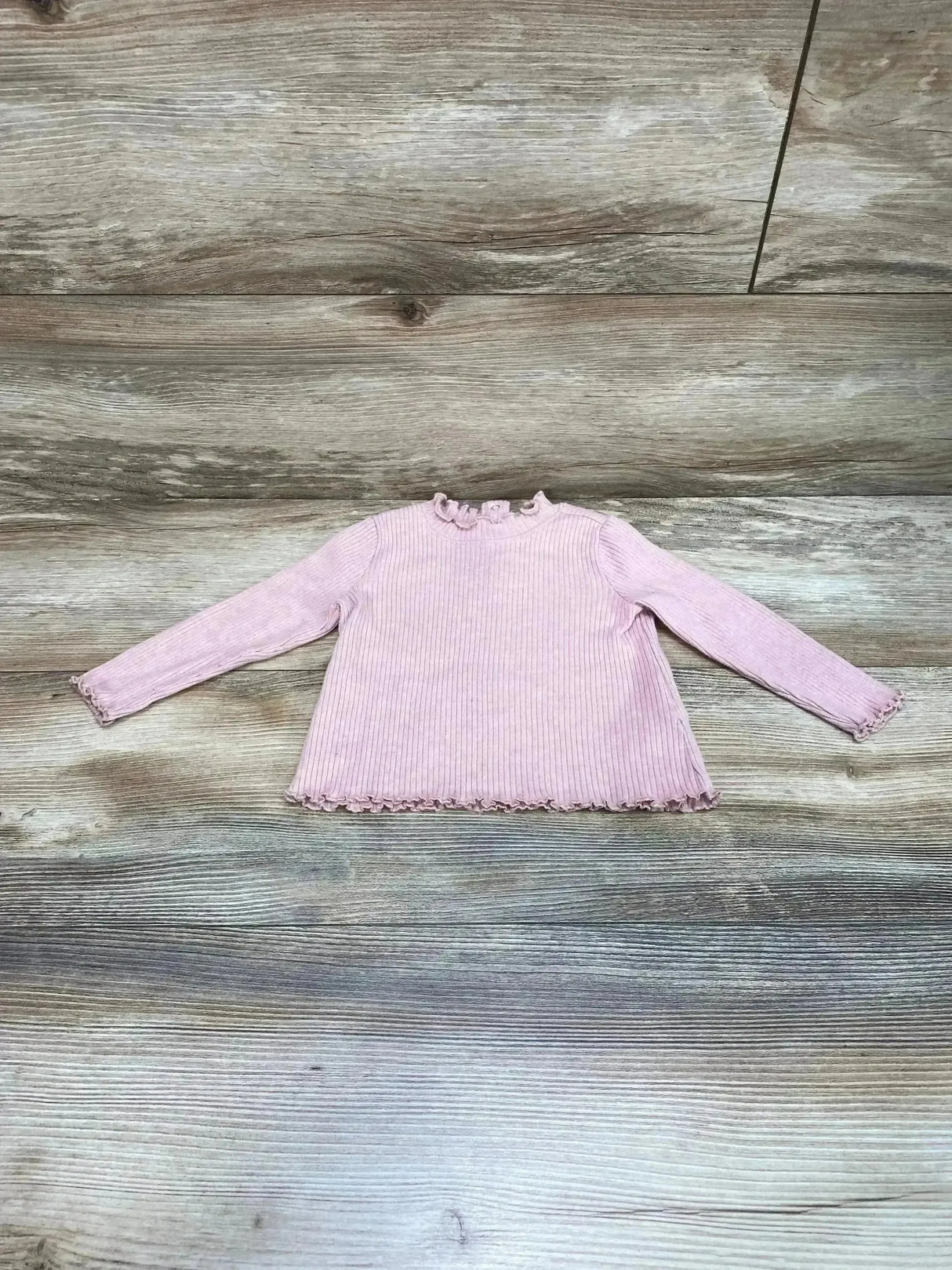 Front view of Old Navy ribbed baby shirt showcasing lettuce-trim ruffles at collar, cuffs, and hem, size 6–12 months on wood-look floor