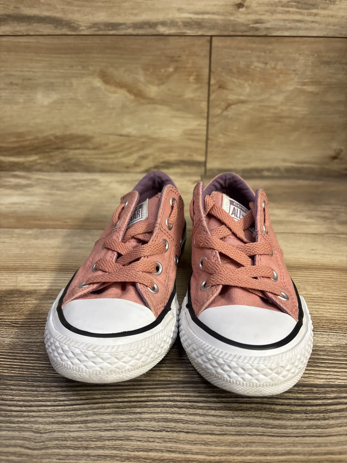 Front view of a pair of pink Converse Chuck Taylor All Star Maddison sneakers with white rubber toe caps and soles on wood
