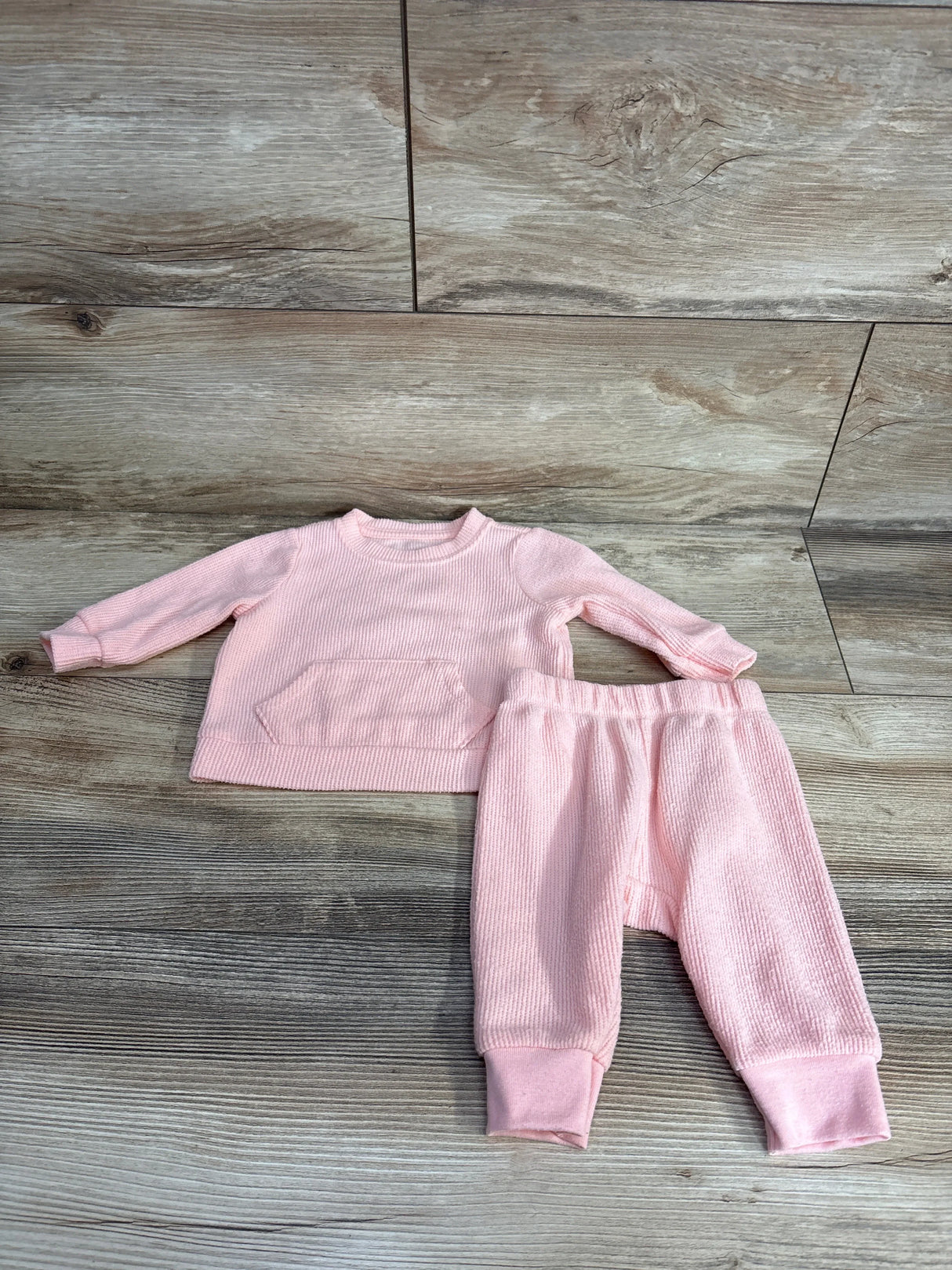 Pink ribbed long sleeve baby outfit set with pants on wooden floor