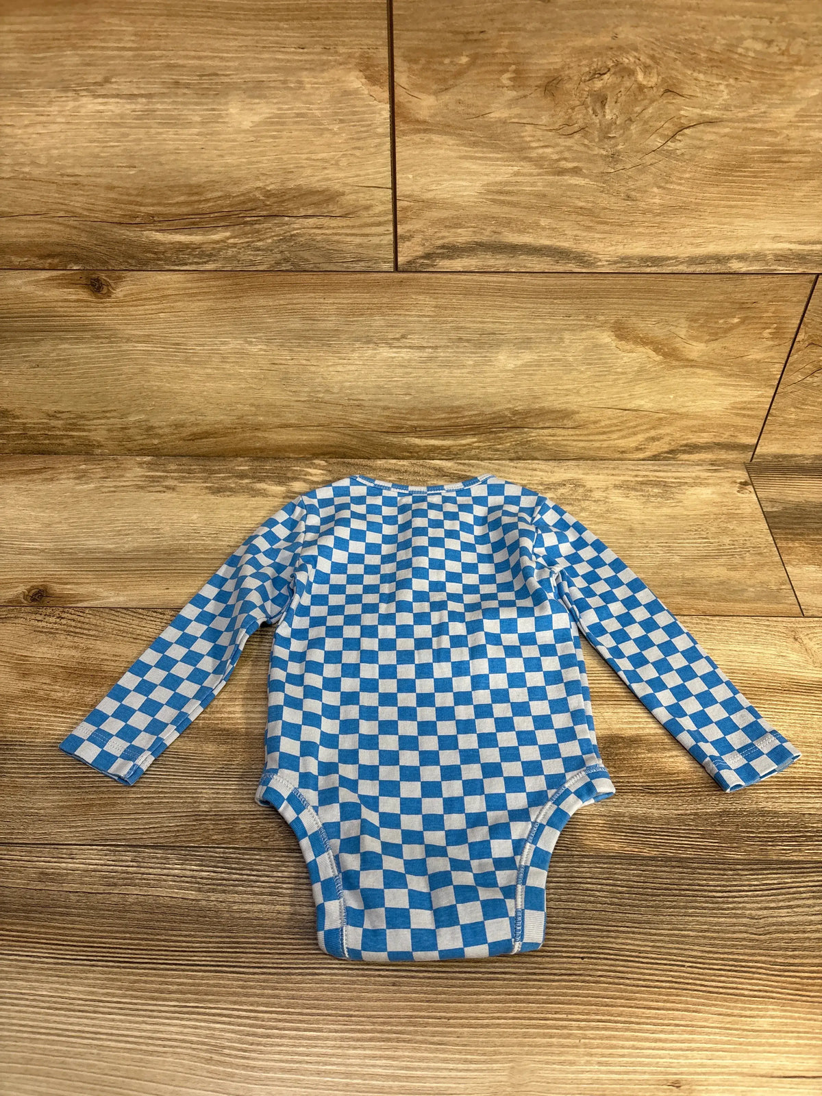 Old Navy blue and white checkered long sleeve baby bodysuit on a wood background