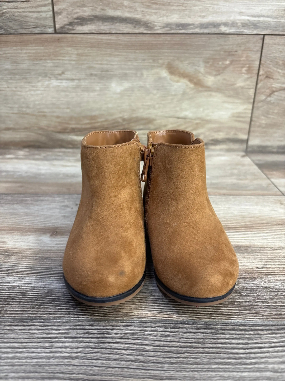 Front view of Cat & Jack Penelope boots in brown showcasing side zippers with wood-look floor background