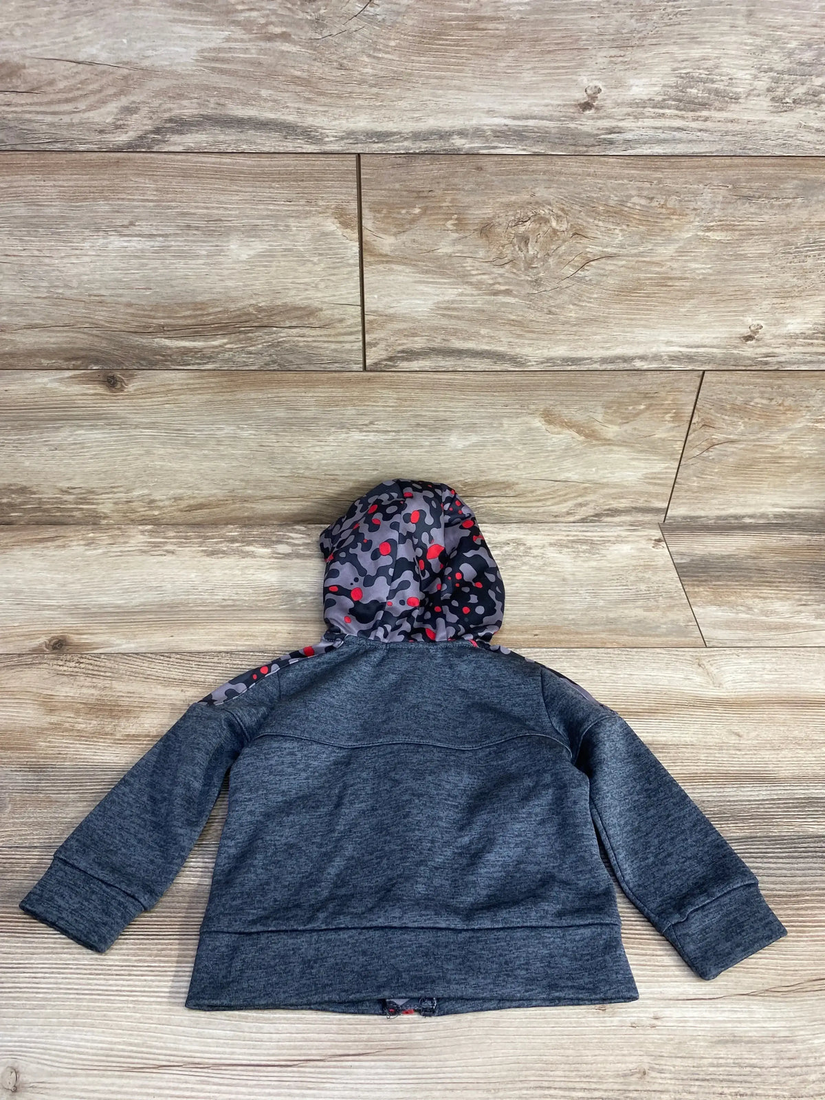Kids gray hoodie with colorful camo-print hood and shoulder detail, laid flat on wood floor