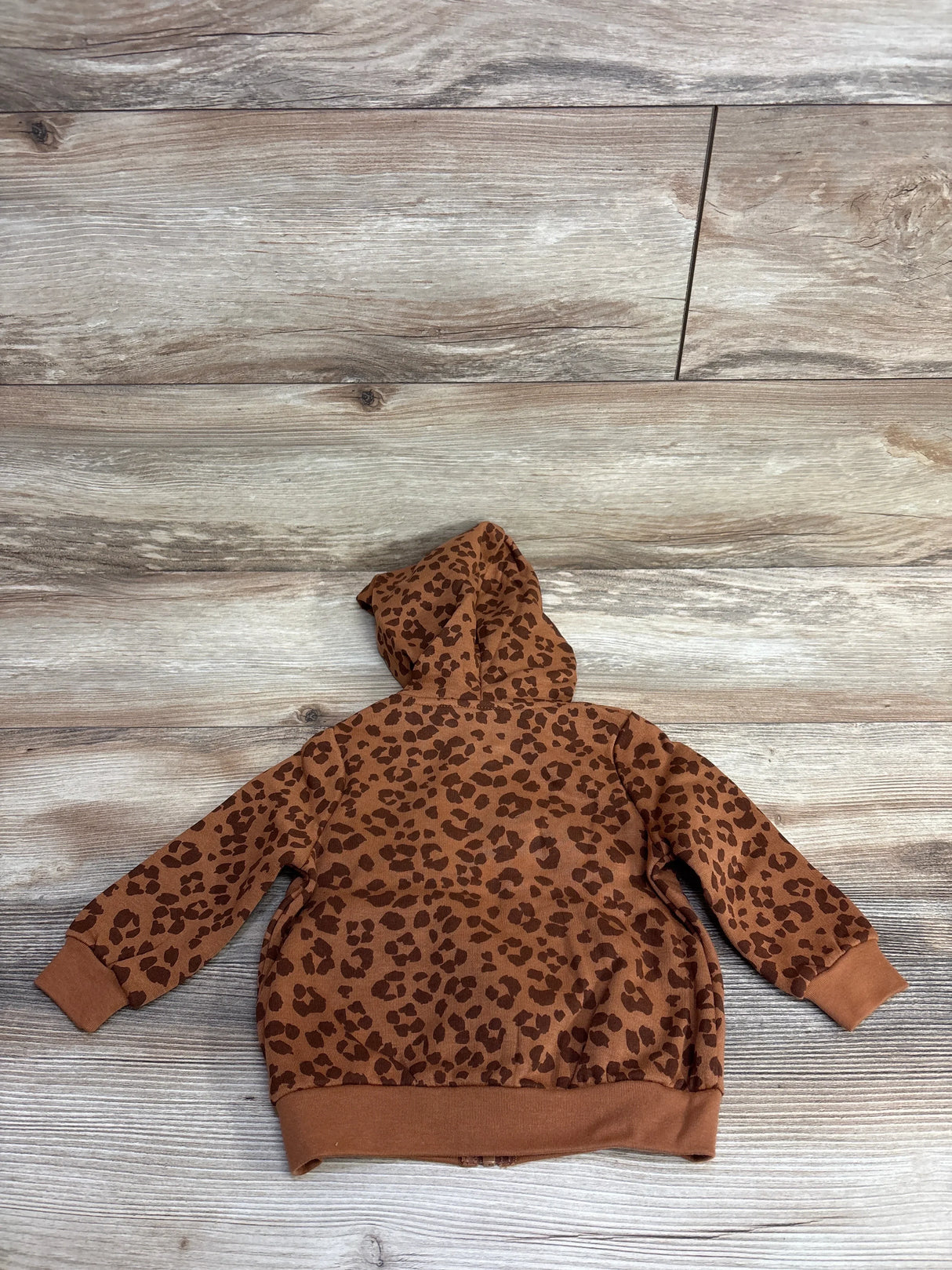 Brown leopard print kids hoodie sweatshirt with hood, laid flat on wood floor