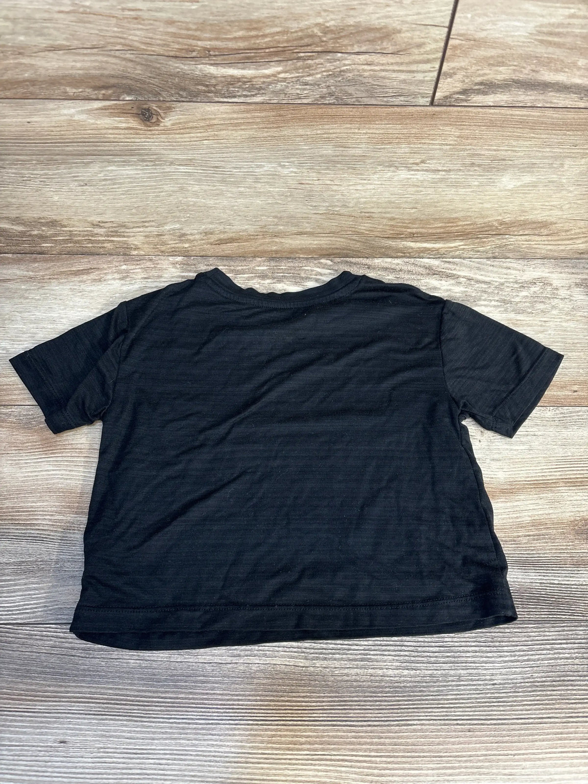 Back view of Reebok black toddler short-sleeve active shirt, size 4T, plain back and crew neck laid flat on wooden floor