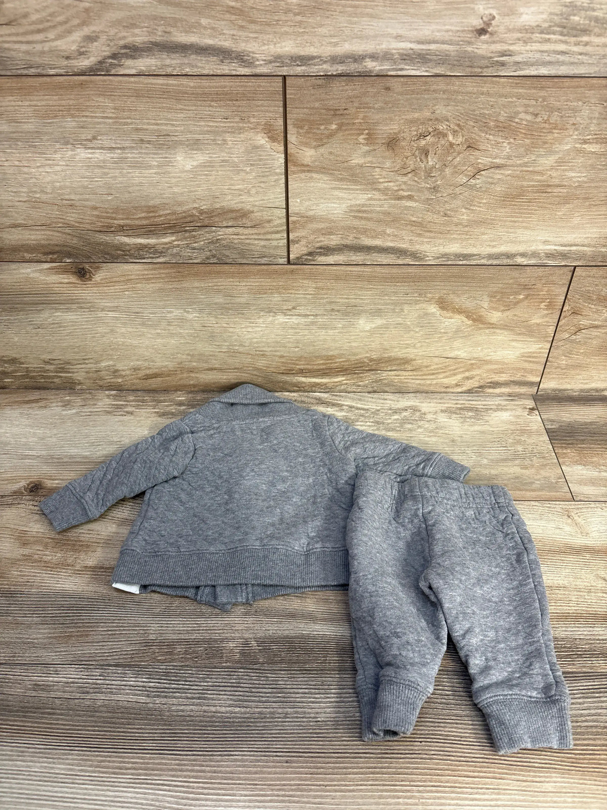 Back view of Carter’s grey quilted jacket and pants set showcasing ribbed cuffs on a wood floor
