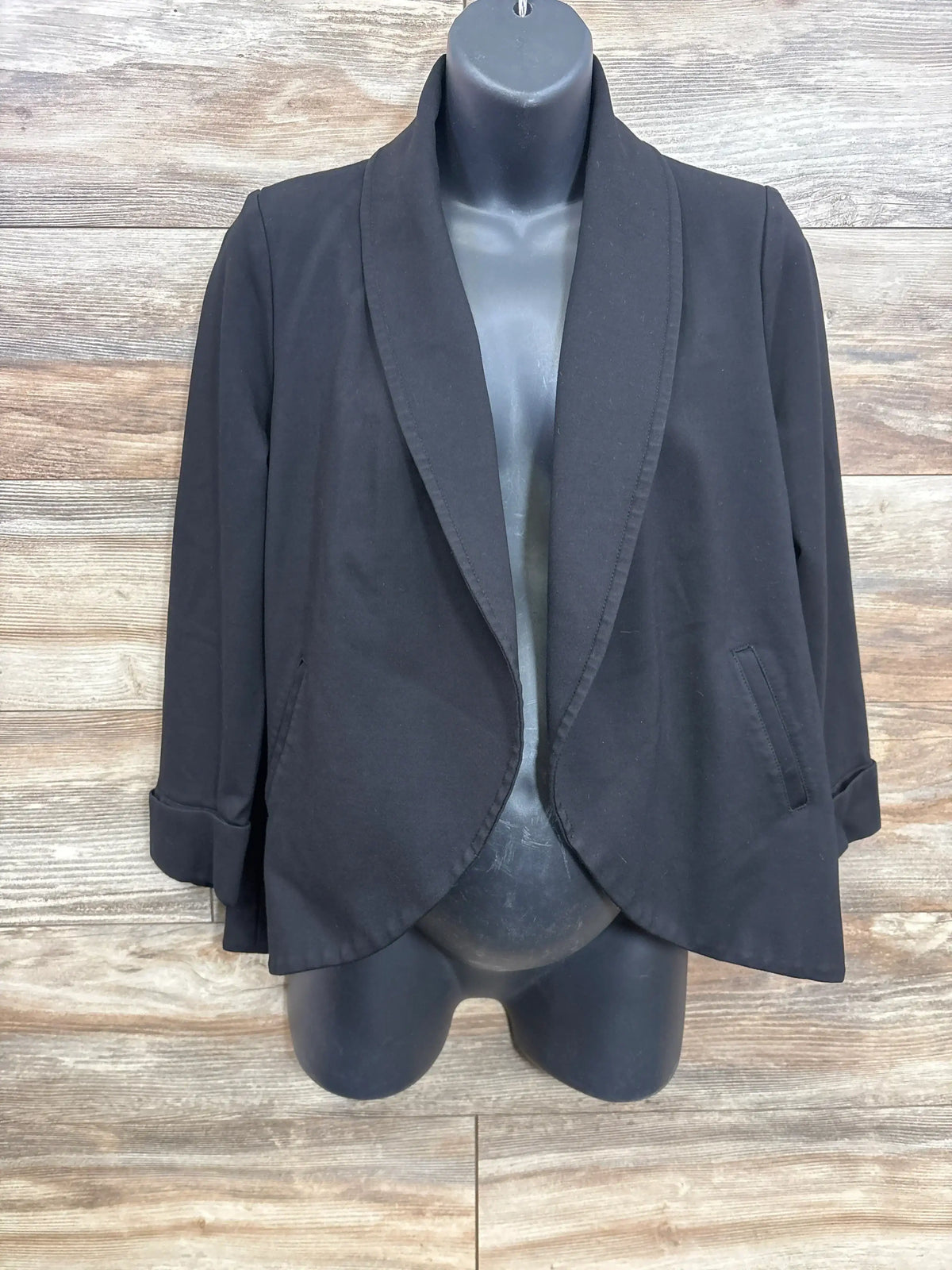 Black open front blazer with cuffed sleeves on mannequin, wood background