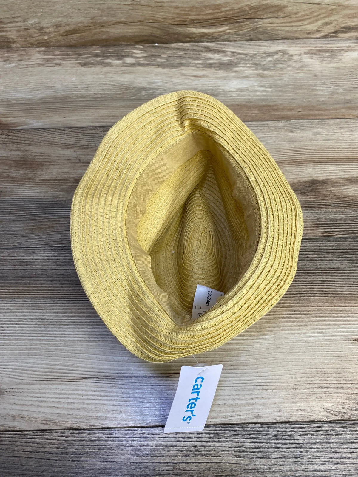 Yellow woven sun hat for toddlers with Carter's brand tag on wooden background