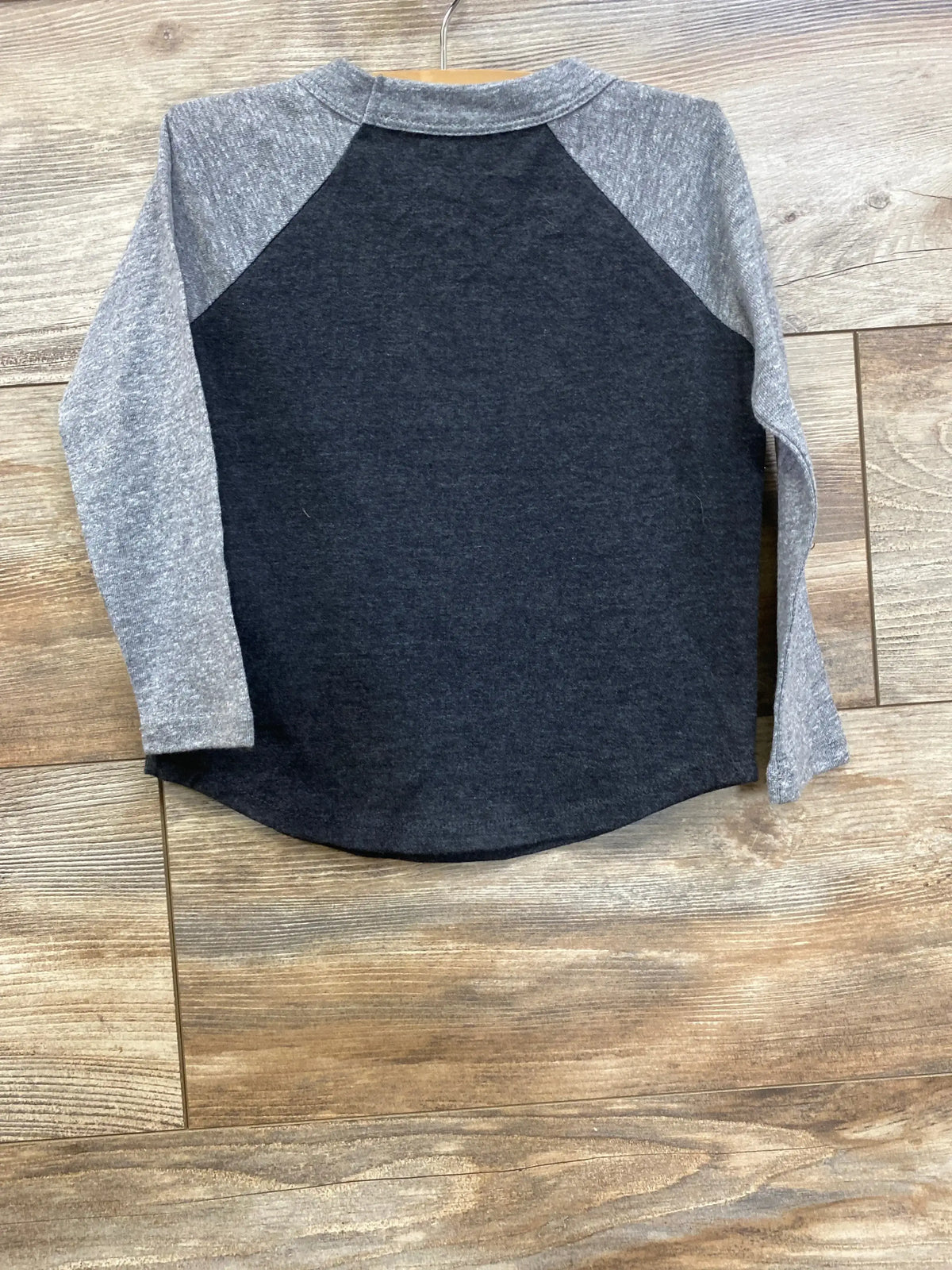 Kids long sleeve raglan shirt with grey sleeves and black body on wood background
