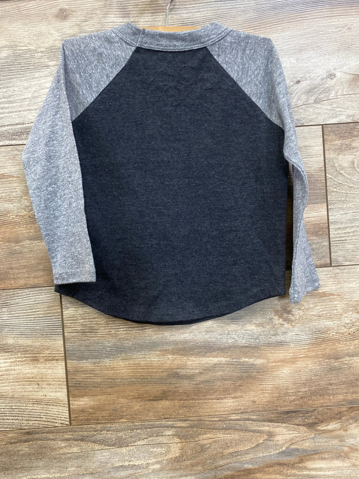 Kids long sleeve raglan shirt with grey sleeves and black body on wood background