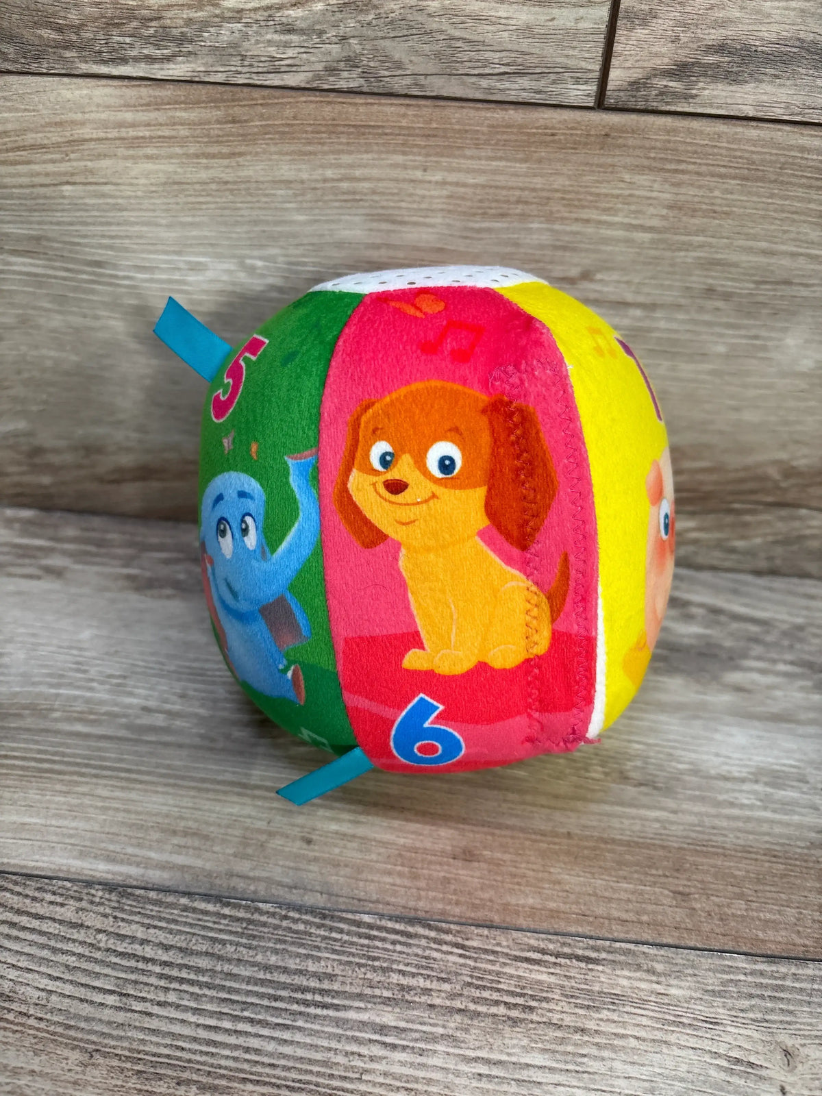 Angled view of Move2Play Interactive Soft Ball showcasing colorful animal character panels on a wood-grain background