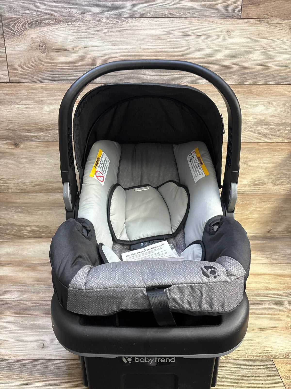 Top-front view of Baby Trend EZ-Lift PLUS infant car seat in Dash Black showing insert, carry handle and base on wood floor