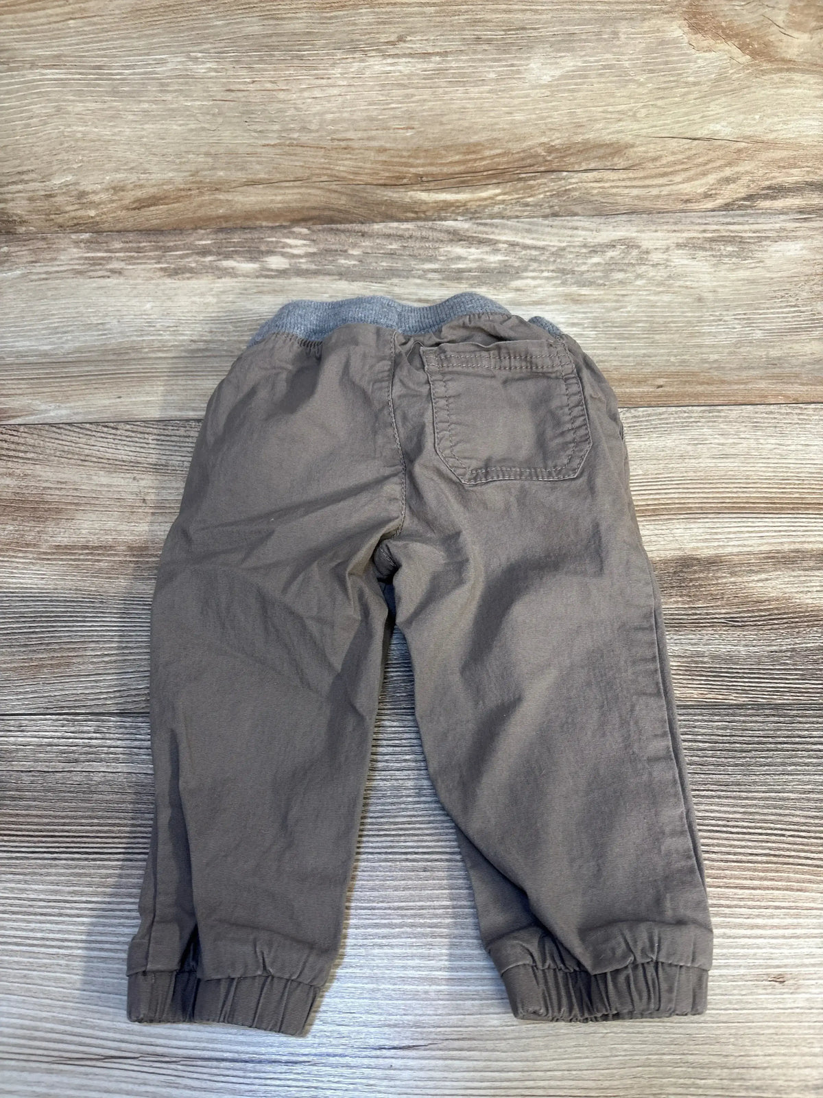 Gray toddler pants with elastic waistband and single back pocket on wood background