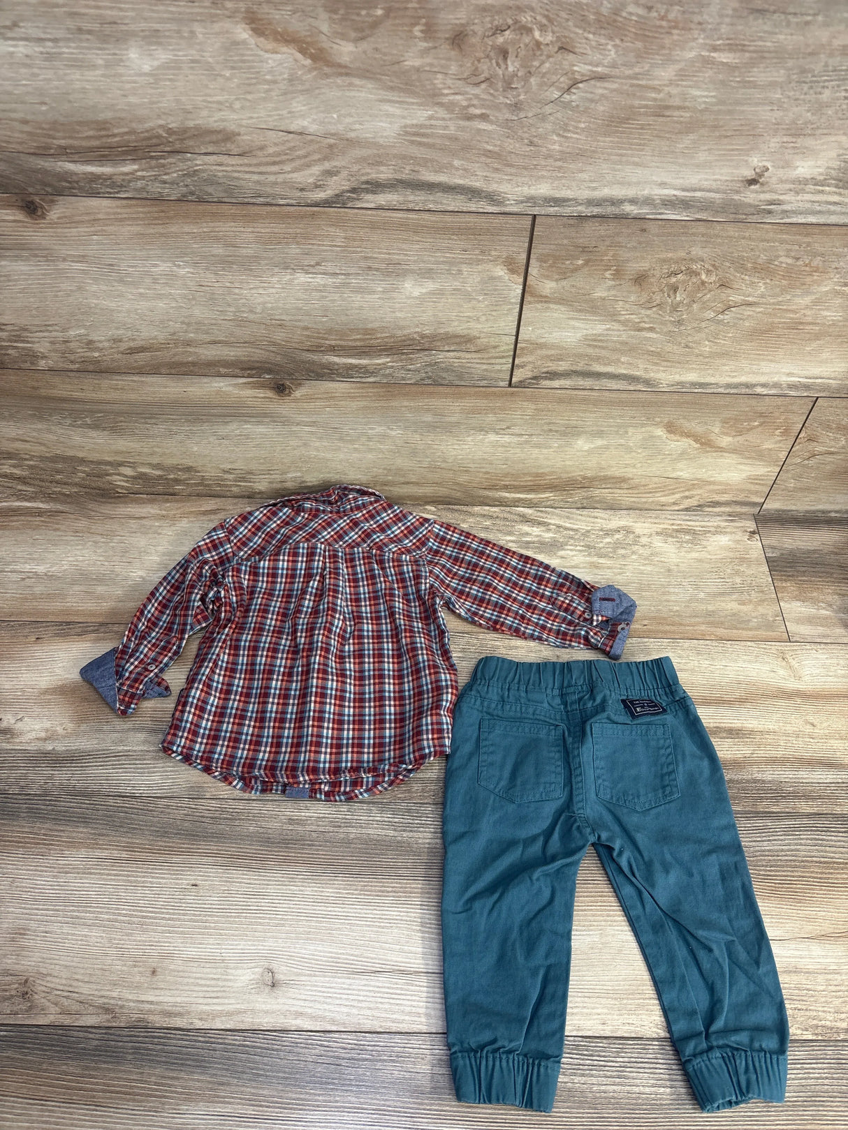 Plaid long sleeve shirt and teal pants for kids on wooden floor