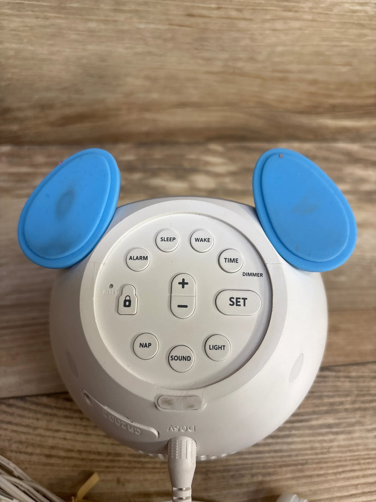 Top view of WindFlyer OK to Wake clock showing sleep, wake, alarm and time buttons, blue ear accents, on wooden surface