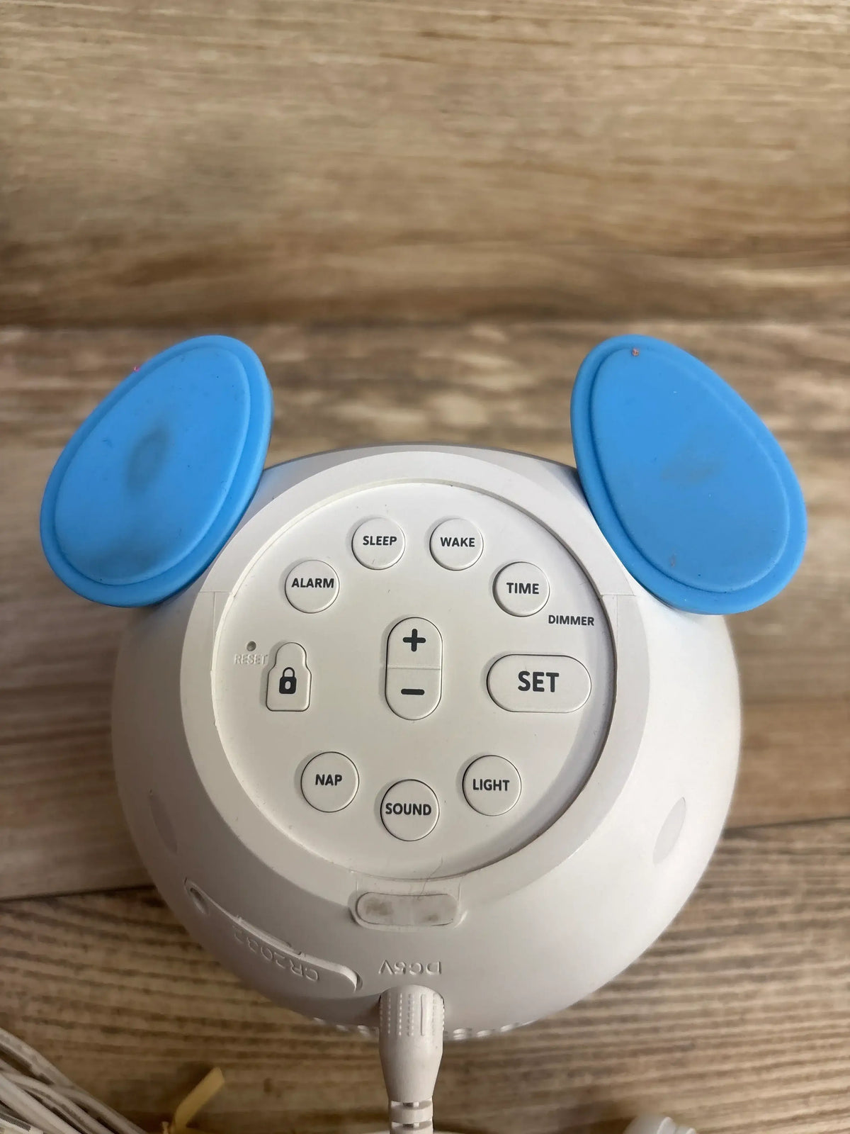 Top view of WindFlyer OK to Wake clock showing sleep, wake, alarm and time buttons, blue ear accents, on wooden surface