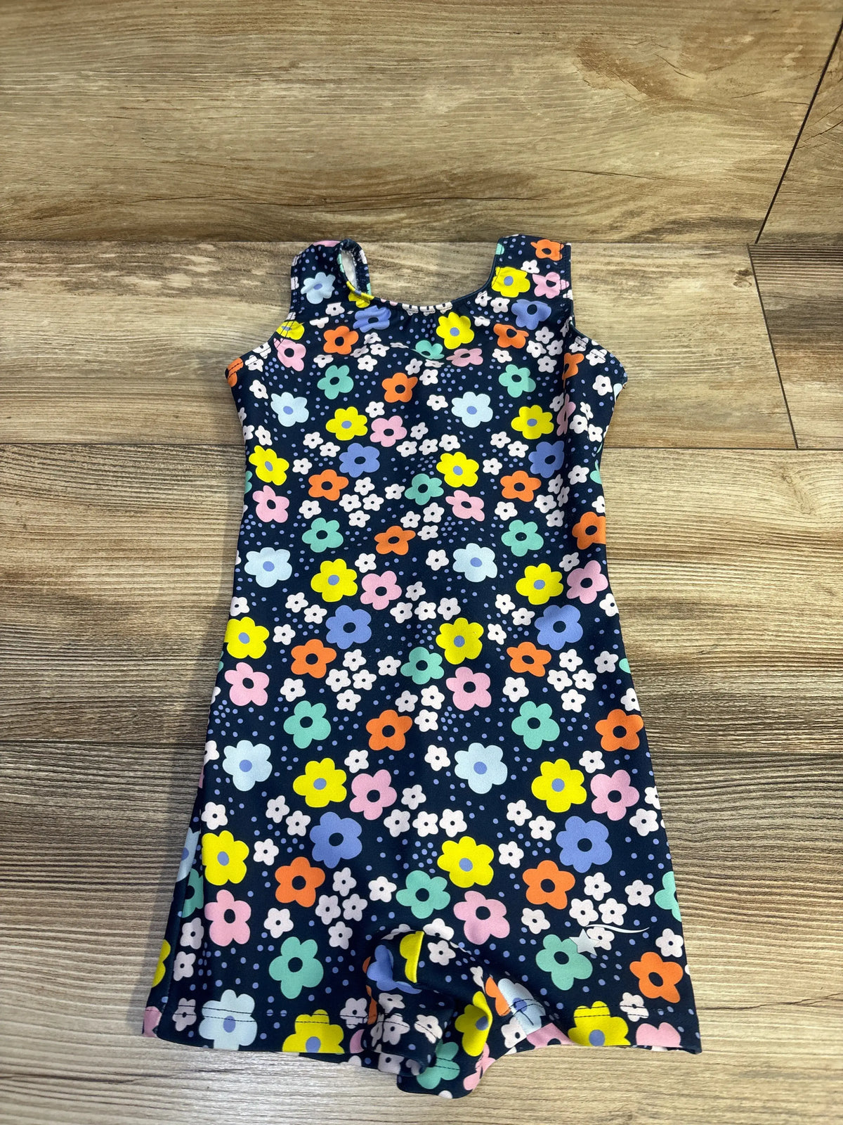 Flat lay of Destira navy girls leotard size 5T showcasing multicolored floral print and tank-style straps on wood floor
