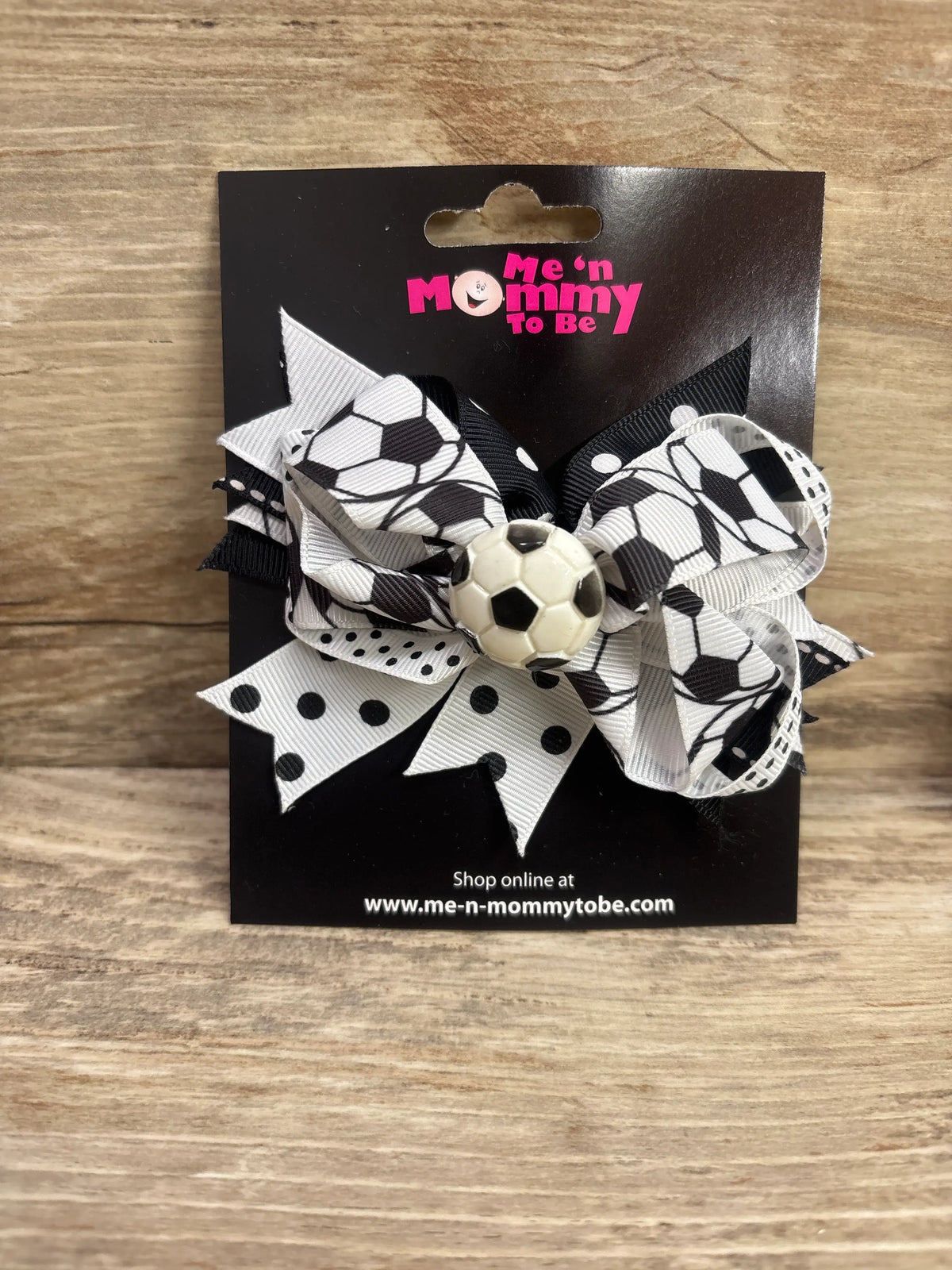 Front view of soccer ball applique layered hair bow with black-and-white soccer-print ribbons on a display card