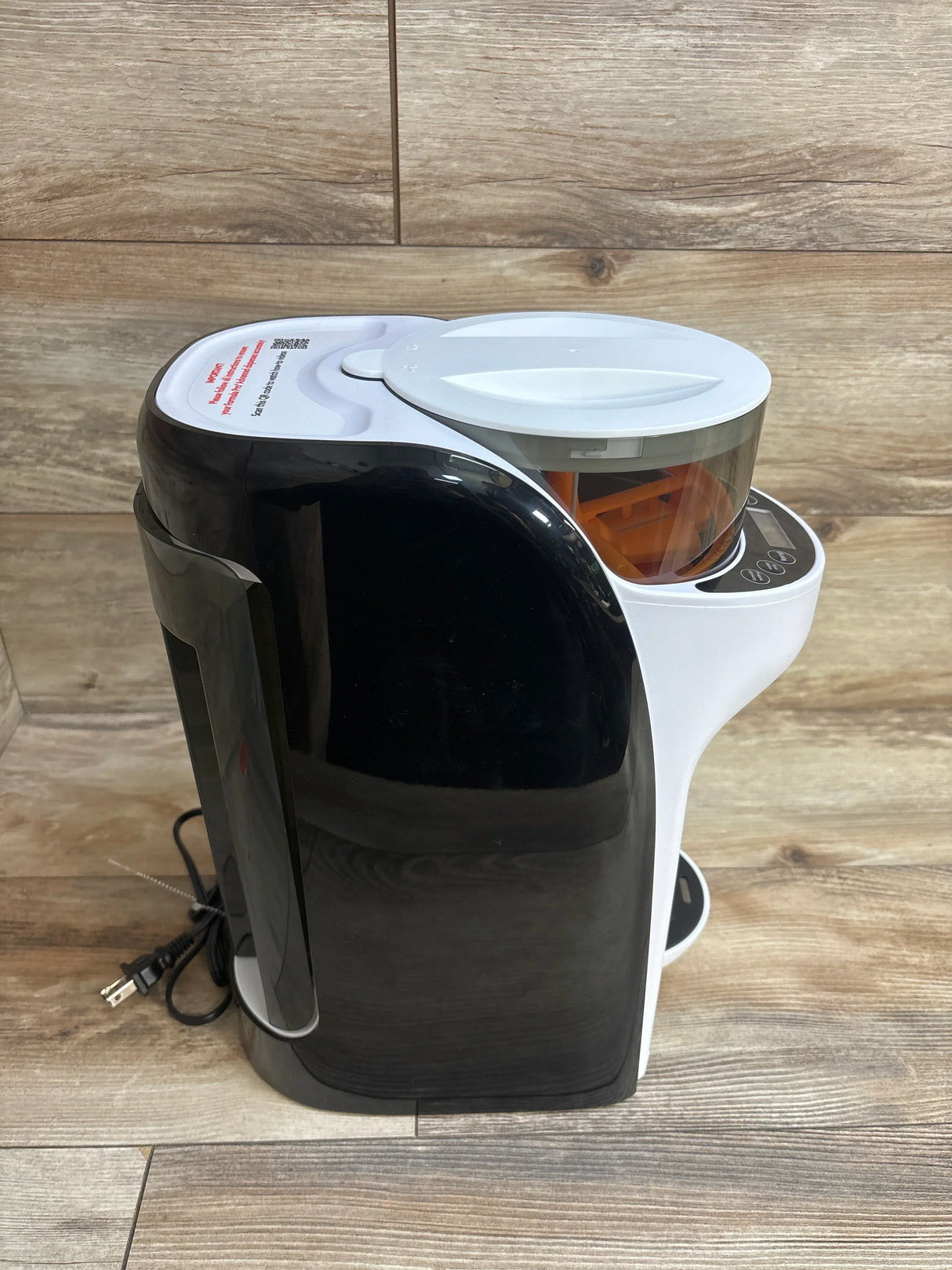 Modern black and white electric coffee grinder machine on wooden surface