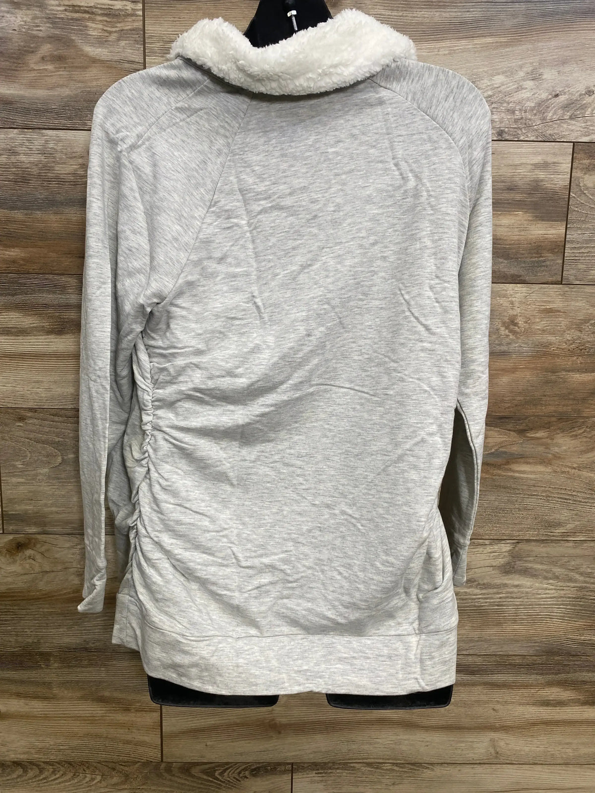Back view of Isabel maternity grey sweatshirt with sherpa snap collar, side ruching and long sleeves on wood background