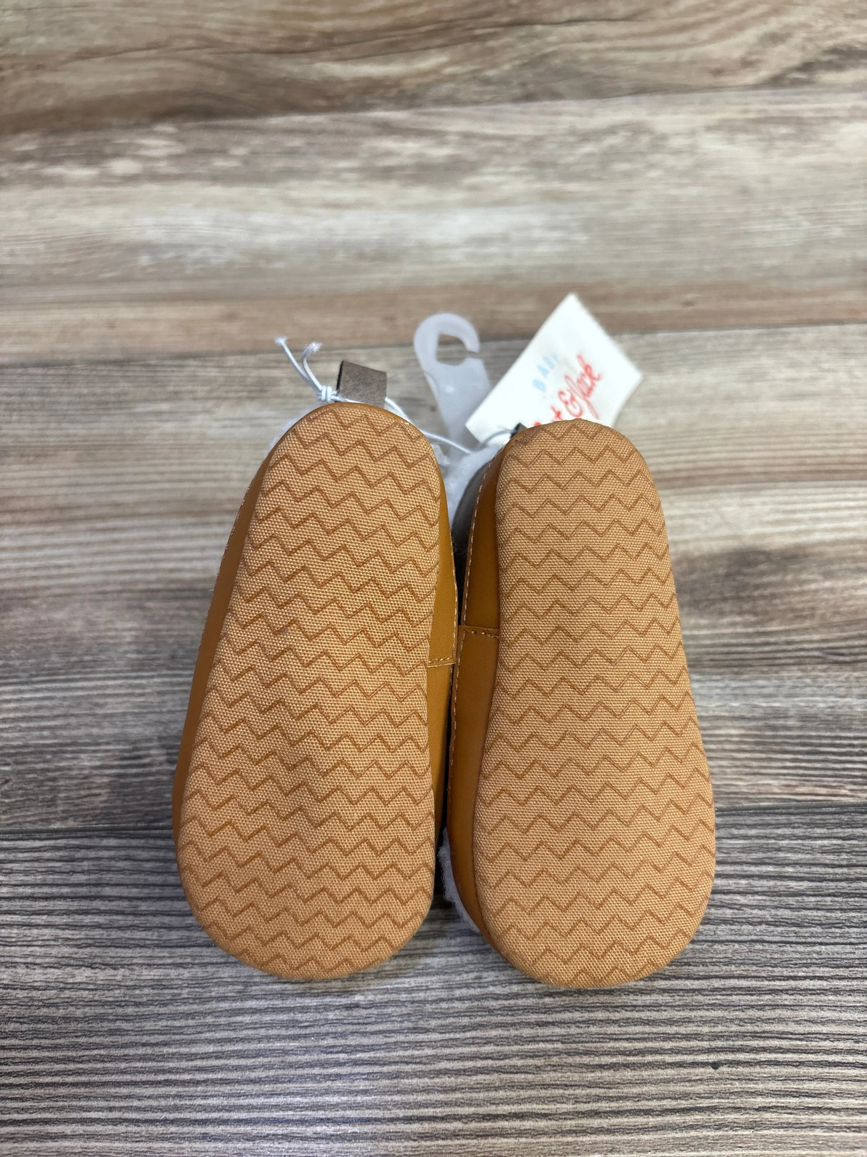 Top-down view of Cat and Jack Sherpa high-top crib shoes size 3-4C showcasing soft zigzag-grip soles on wooden surface