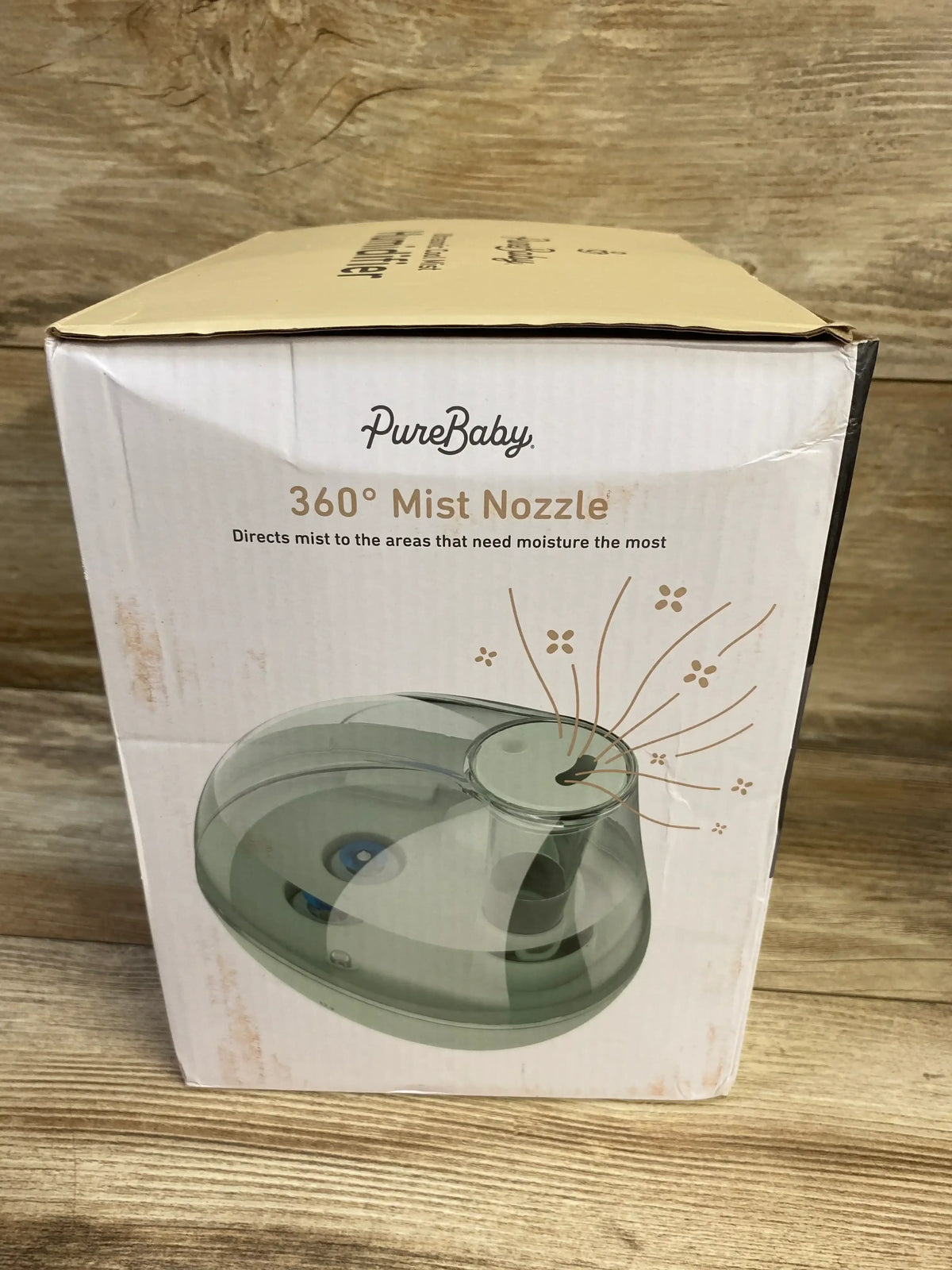 Front view of PureBaby Ultrasonic Cool Mist Humidifier box showcasing 360 degree Mist Nozzle graphic on wooden surface
