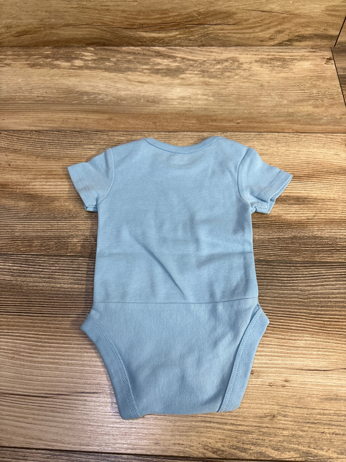 Back view of Hanes Grandpa’s Sidekick bodysuit 0-6M showcasing short sleeves and ribbed snap-closure on wooden background