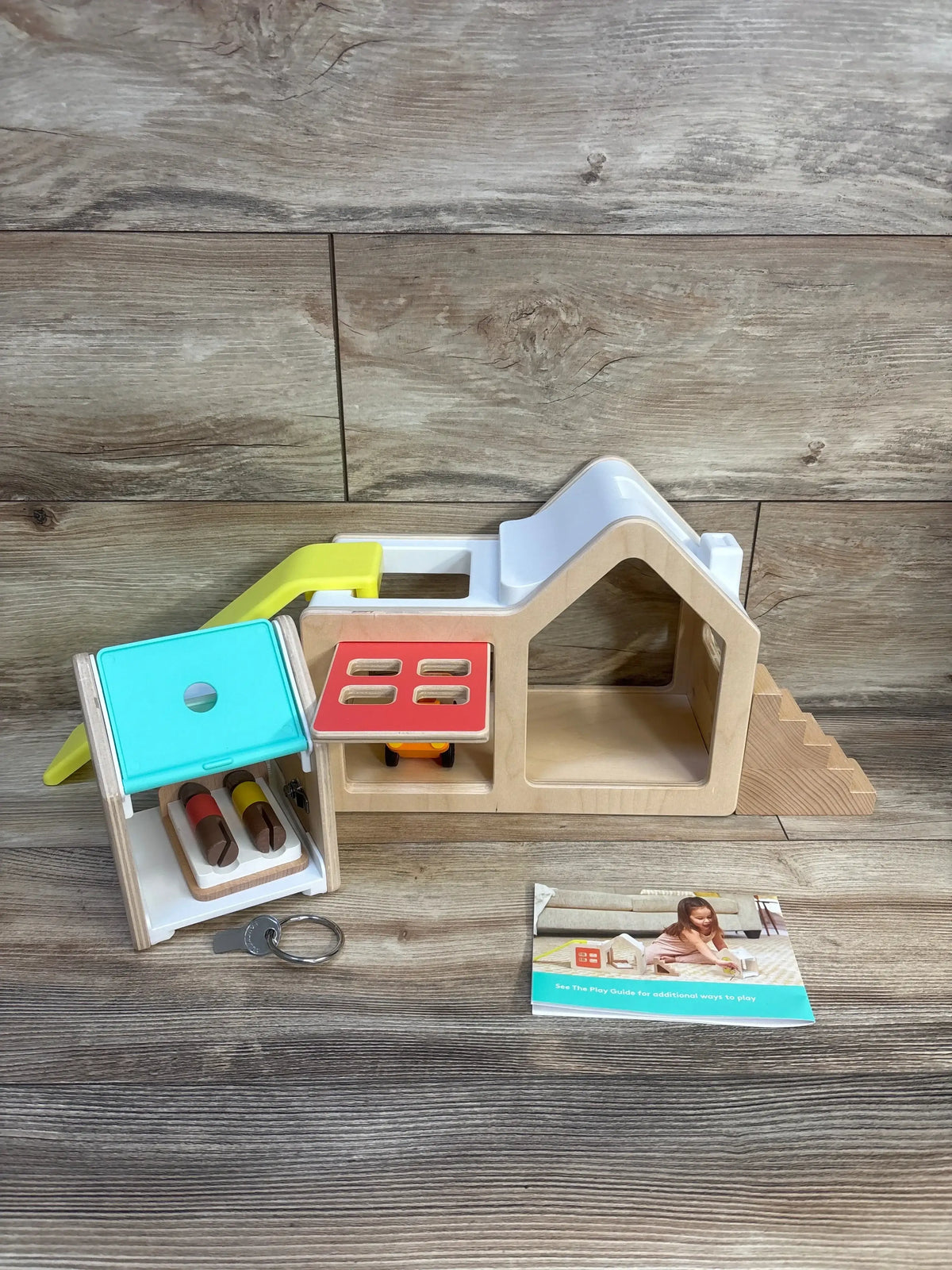 Wooden playhouse toy with colorful doors, keys, and play guide for kids' imaginative play