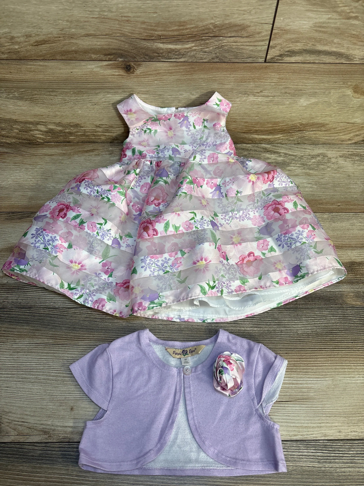 Girls’ floral sleeveless dress with lilac bolero on wood background, spring outfit