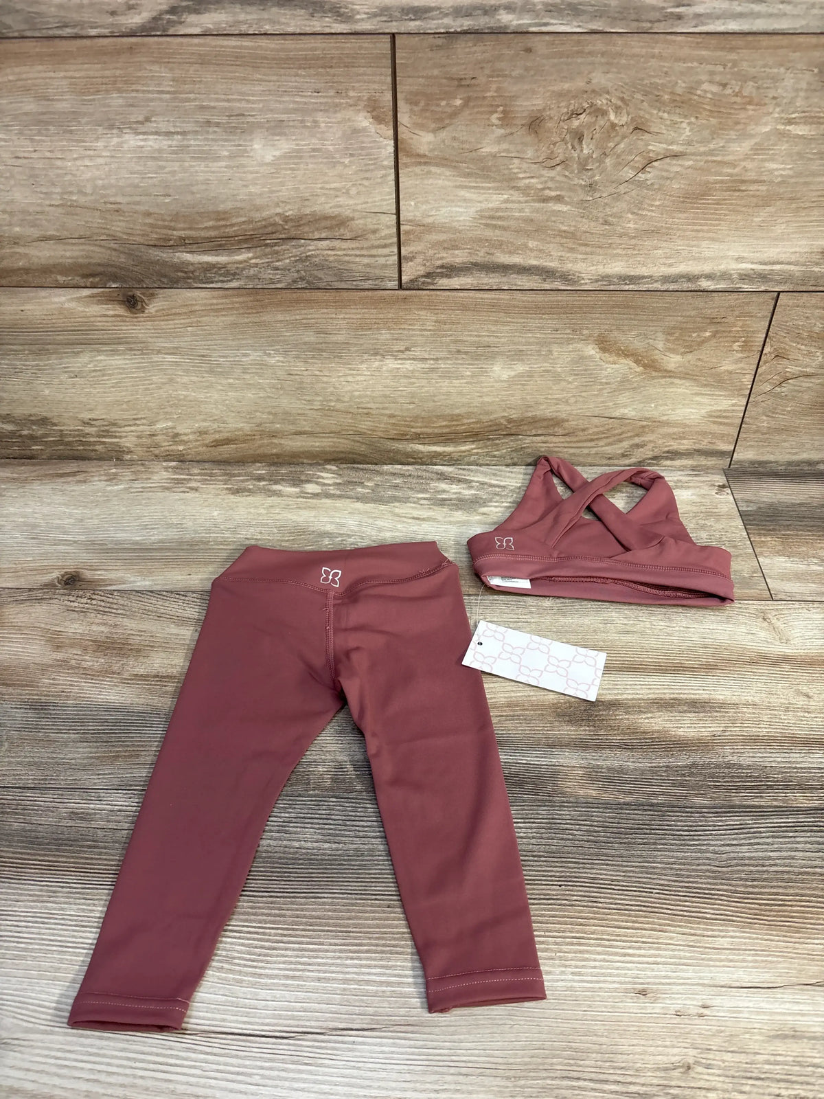 Top view of red Bailey’s Blossoms 2-piece sports bra and leggings set showcasing matching athletic pieces on a wood-look floor