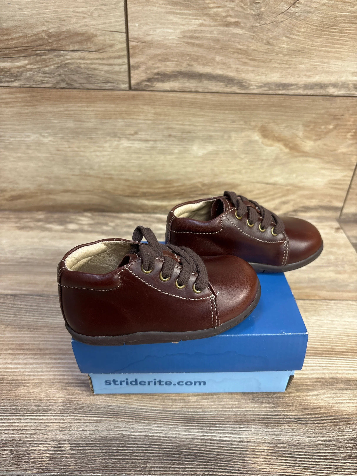 Side view of brown Stride Rite SRTech Elliot toddler sneakers showing leather upper, laces, and padded collar on blue Stride Rite box