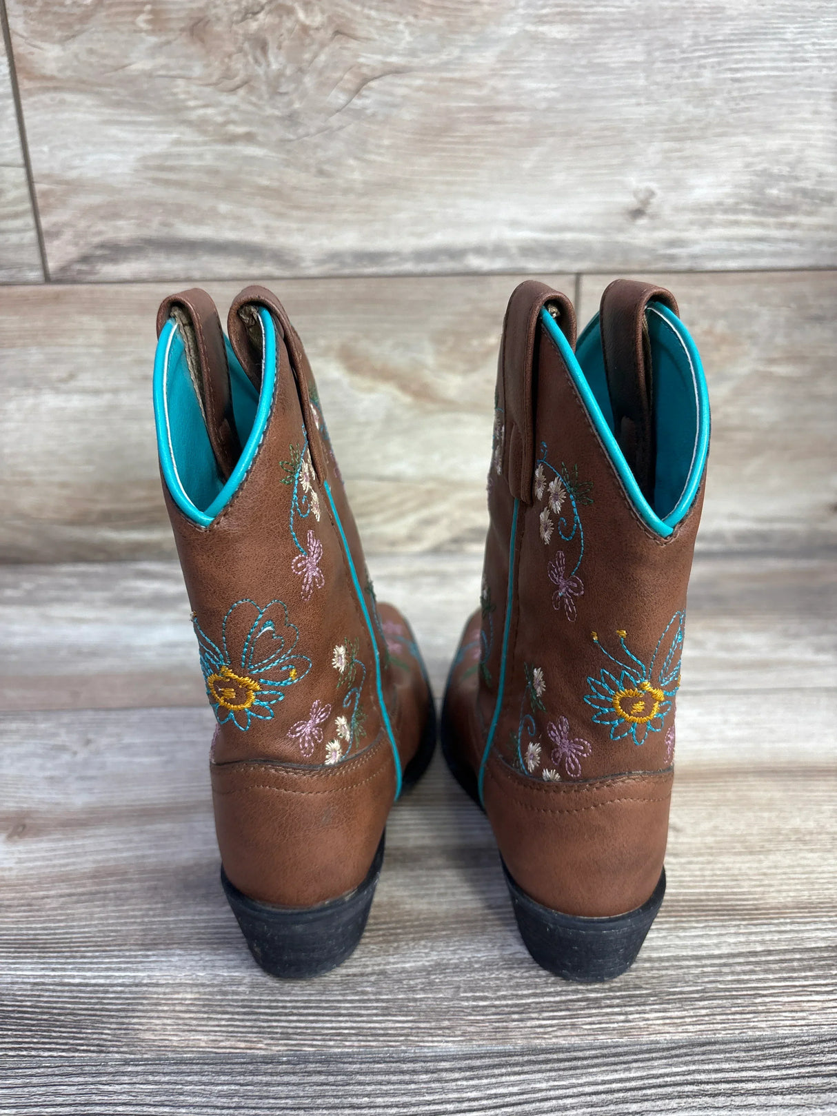 Rear view of Shyanne floral embroidery western boots (child size 10C) showcasing stitched flowers and turquoise piping and lining on a light wood floor