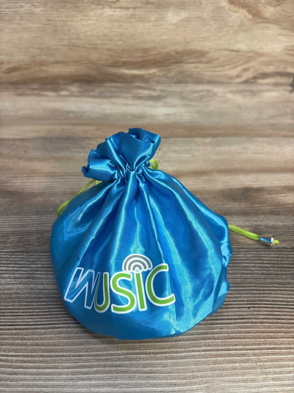 Blue Wusic drawstring pouch with green cord on wood background