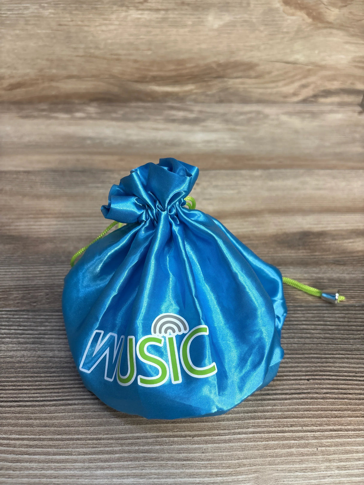 Blue Wusic drawstring pouch with green cord on wood background