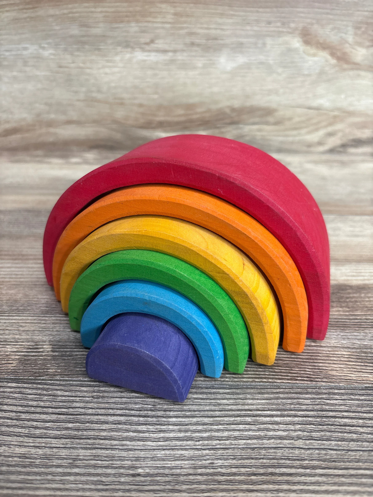 Colorful wooden rainbow stacking toy on wood background, kids educational toy