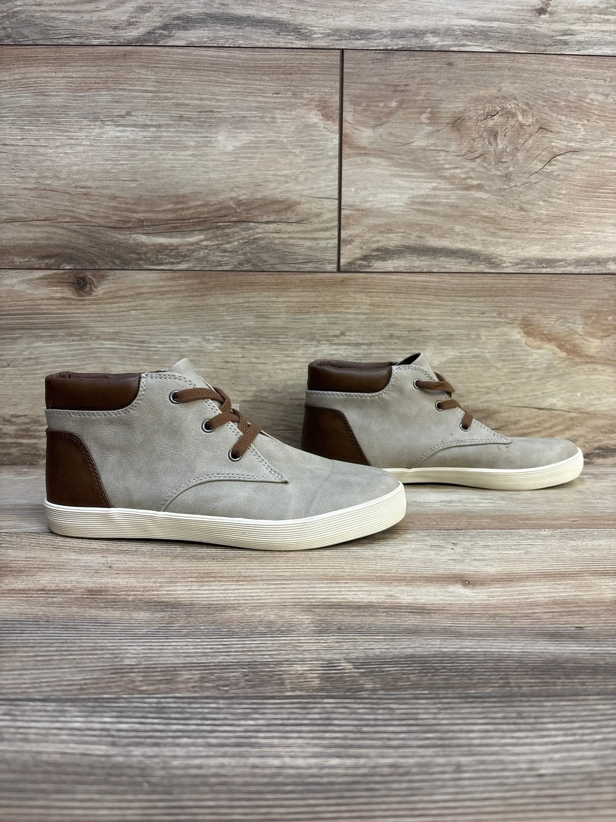 Kids light gray and brown high-top sneakers with rubber soles on wood background