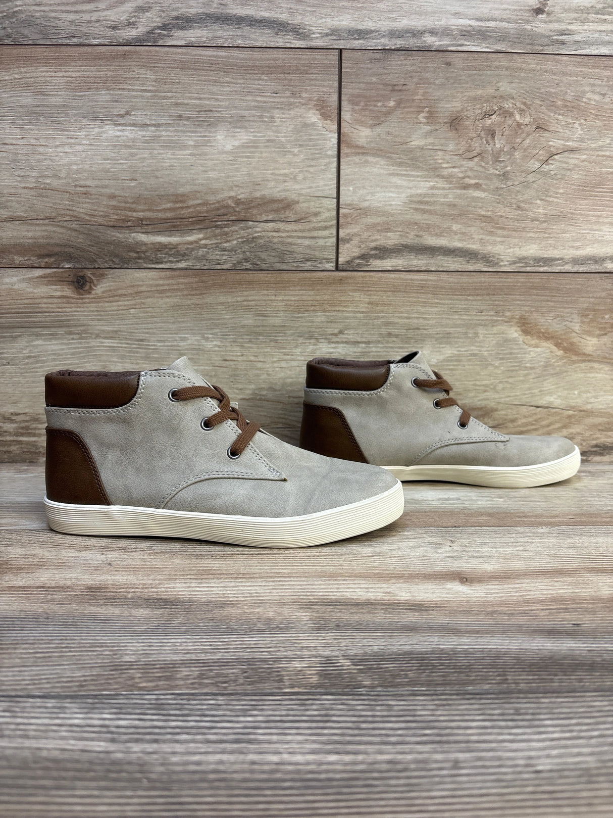 Kids light gray and brown high-top sneakers with rubber soles on wood background