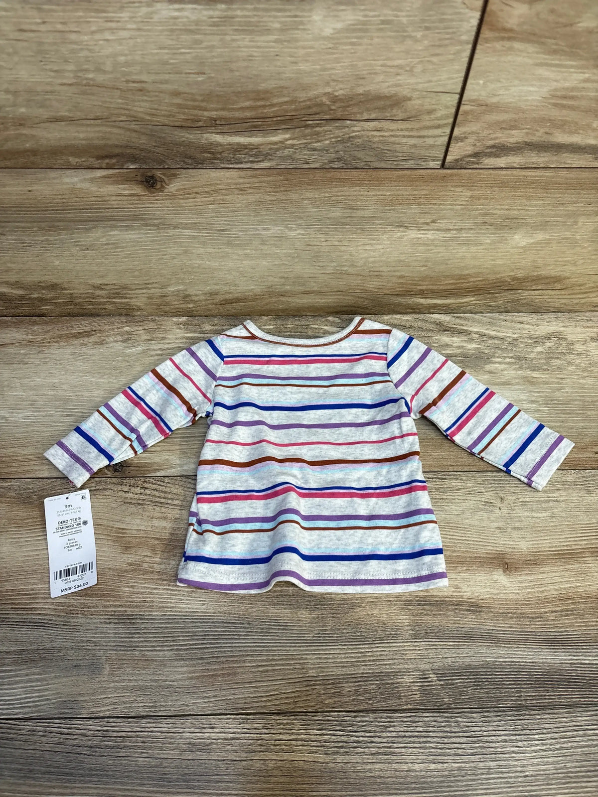 Long sleeve toddler shirt with multicolored horizontal stripes and price tag on wooden background