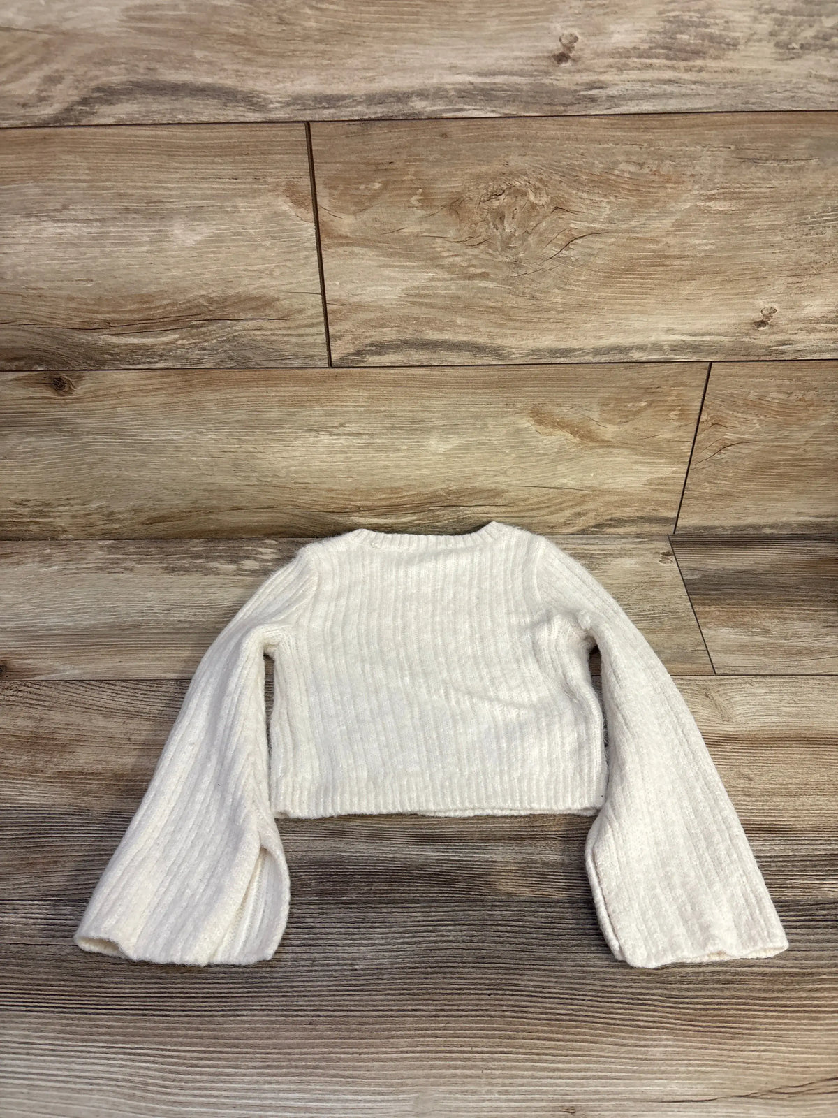Front view of GB Girls knit sweater showcasing ivory ribbed knit and long sleeves with a wood floor background