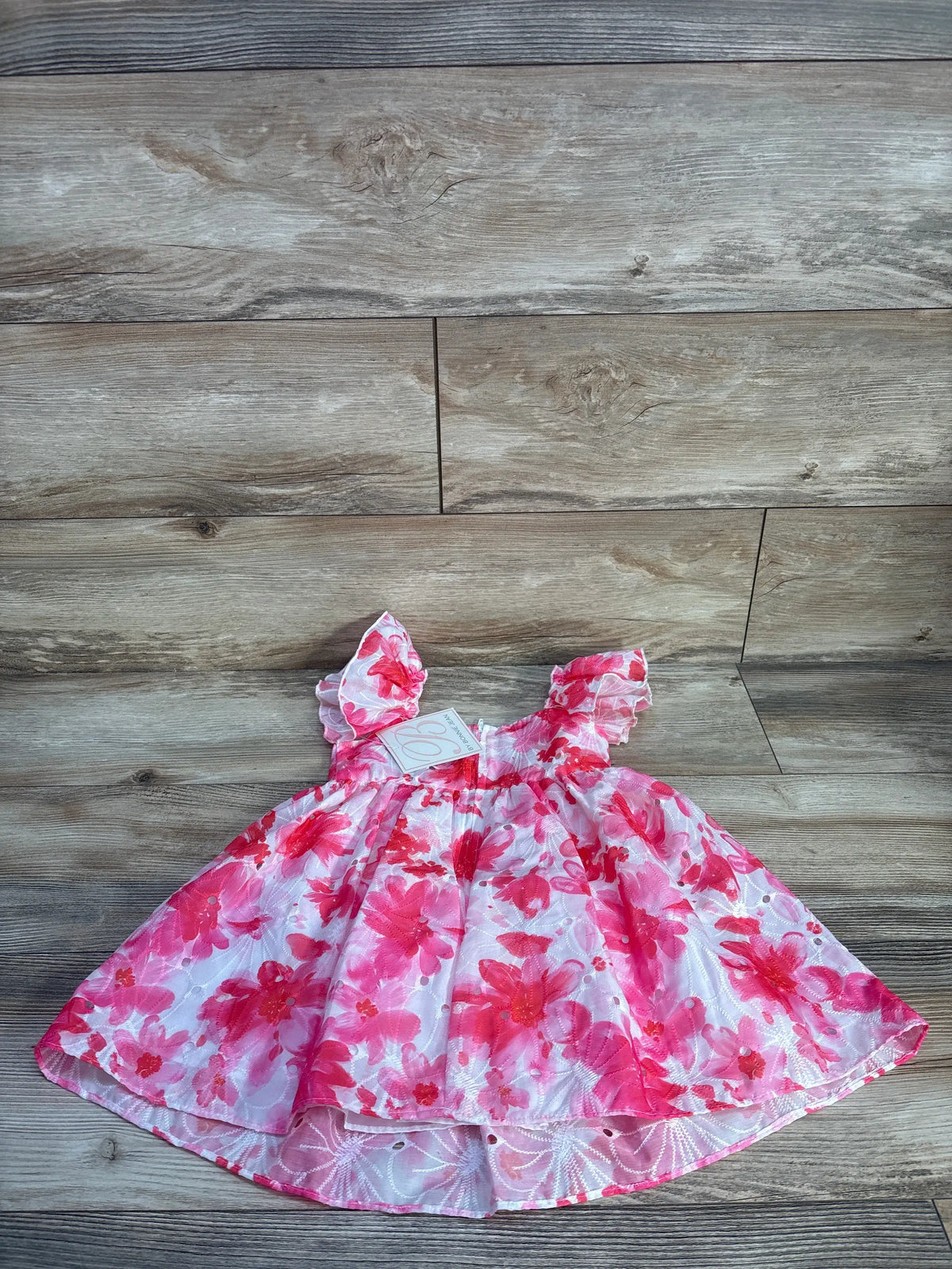 Front view of white 2T toddler dress showcasing pink floral embroidery and layered skirt on wood grain background