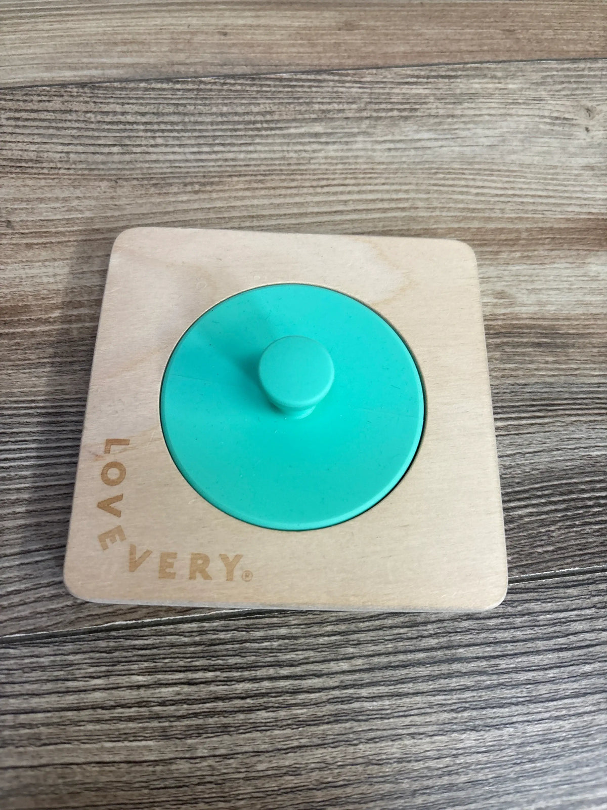 Top down view of Lovevery wooden Montessori baby puzzle showing single green knobbed circle in light wood frame on wood floor
