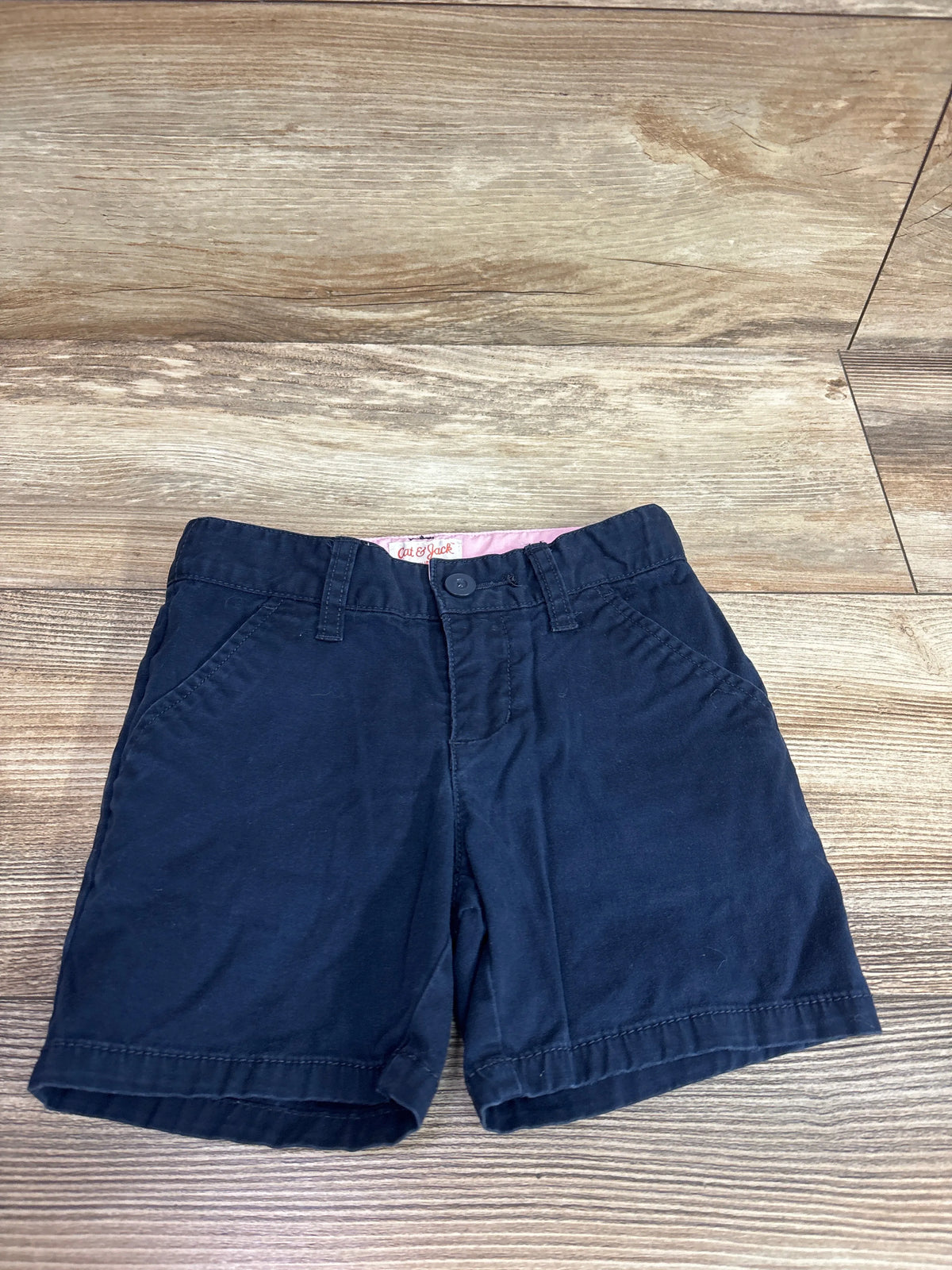 Navy blue Cat & Jack school uniform shorts for toddlers, size 3T, on a wooden surface.