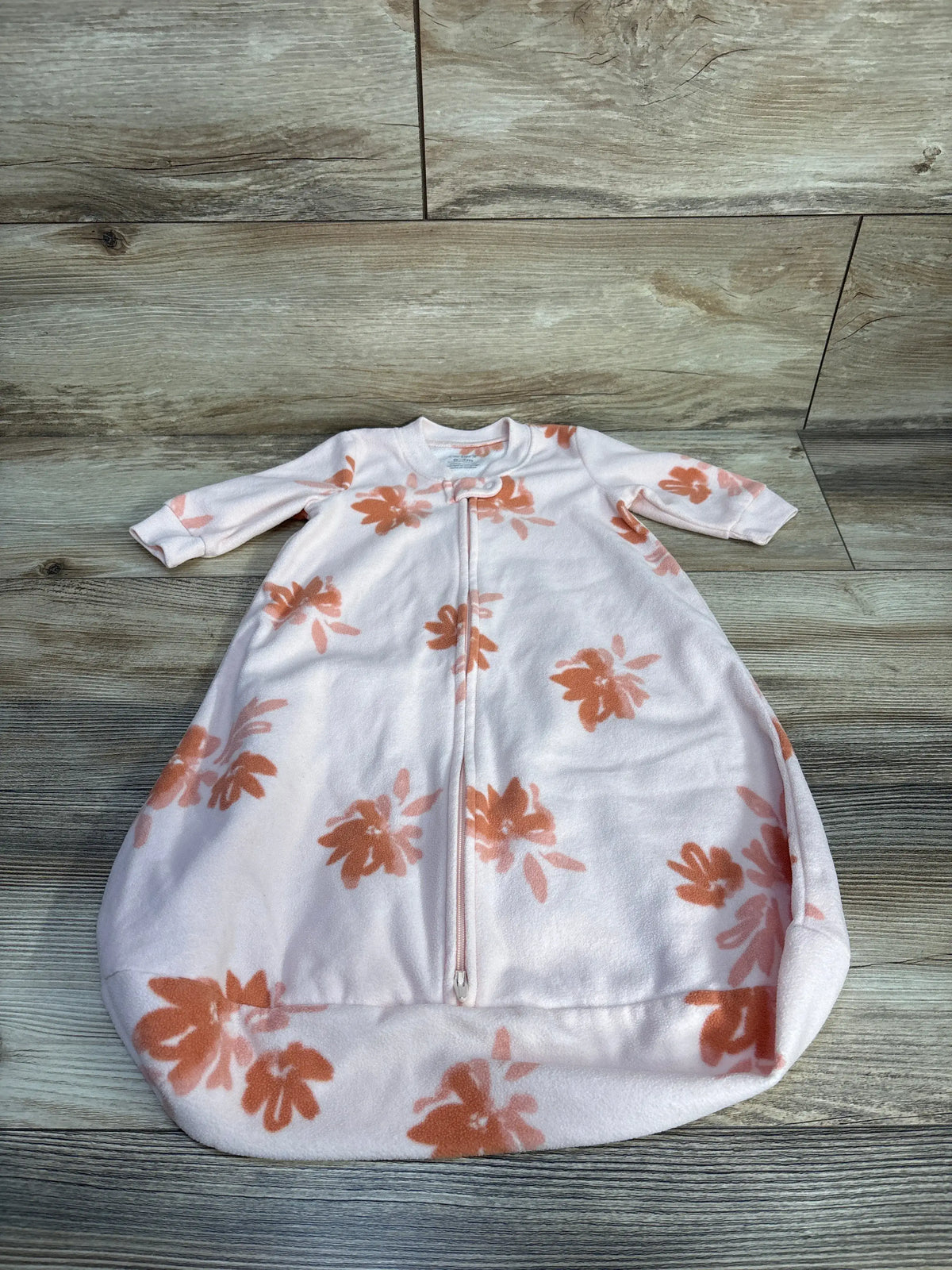 Front view of Carter’s pink floral blanket sleep sack for 0-3 months showcasing its 2-way zipper on a wood floor