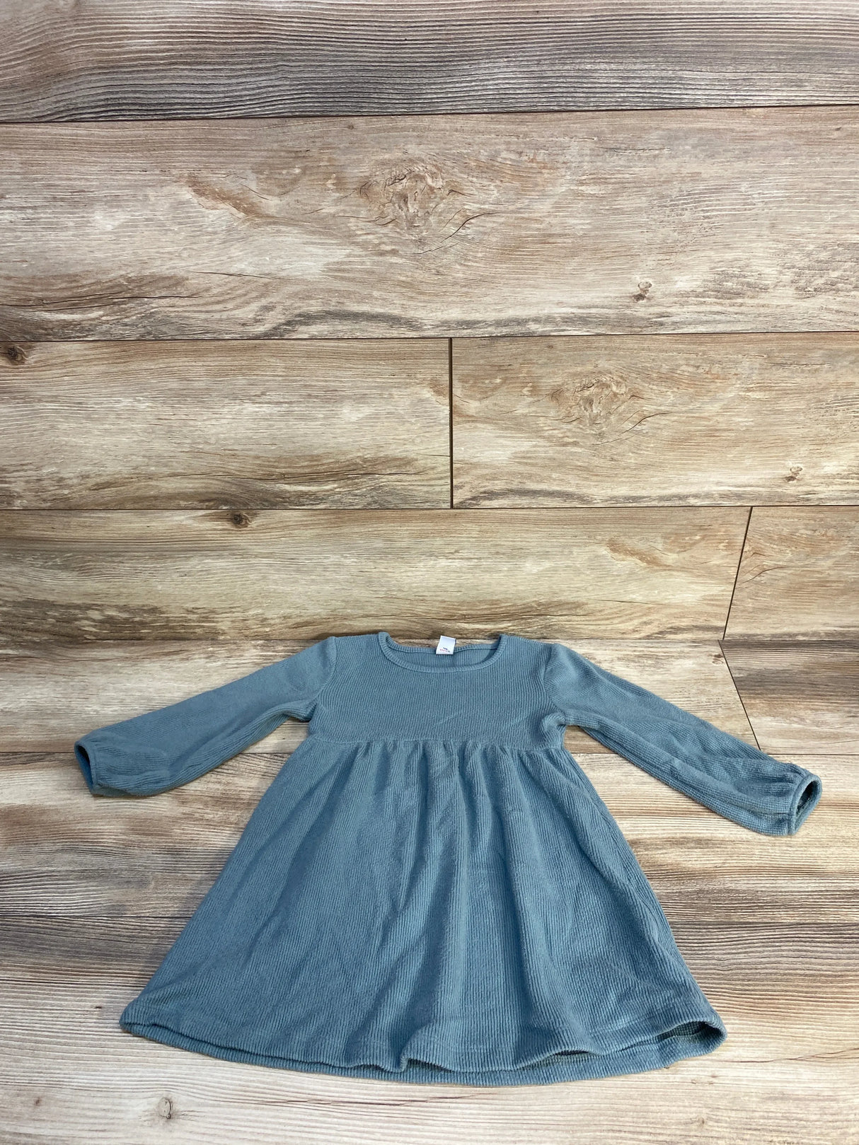 Blue long sleeve toddler girl dress laid flat on wood background, kids clothing resale